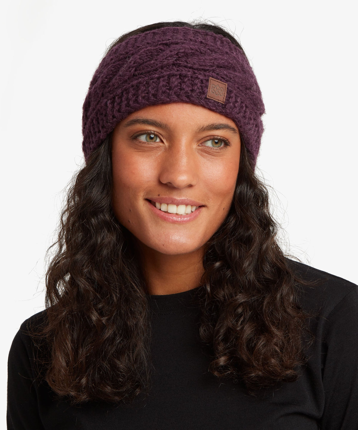 A woman with long, wavy dark brown hair wearing a textured knit beanie.