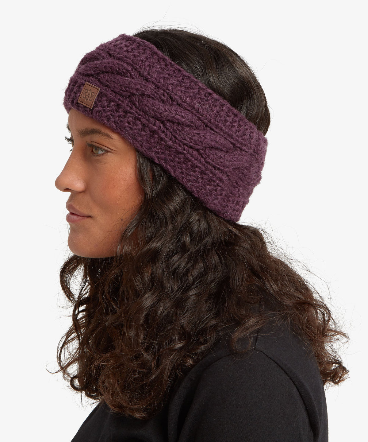 A woman in profile wearing a chunky cable-knit headband in a deep plum purple color.
