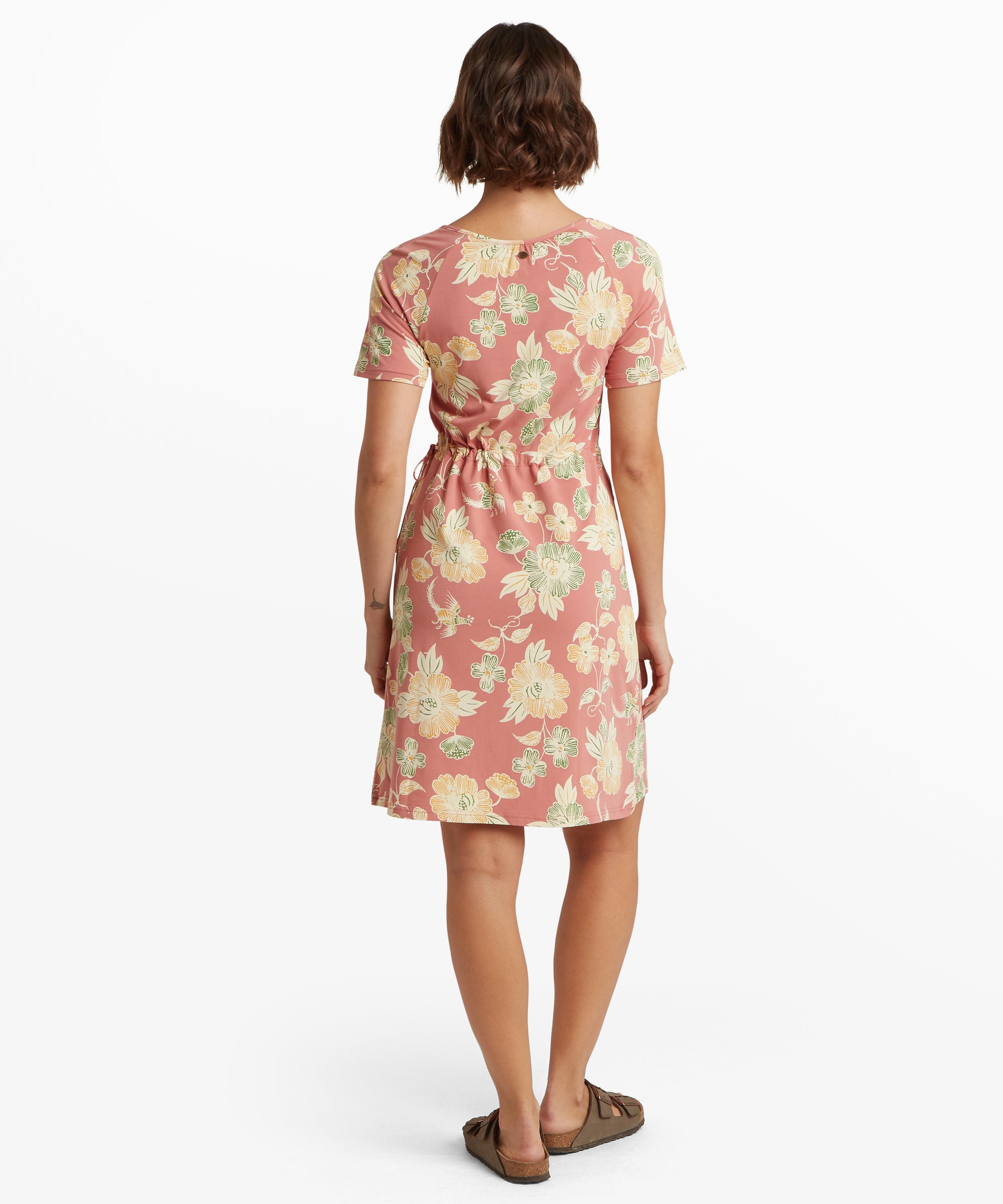 Rear view of a mid‑length pink tank dress with a scoop back neckline and an all‑over tonal scenic illustration. A small round metal decorative tab sits below the neckline.