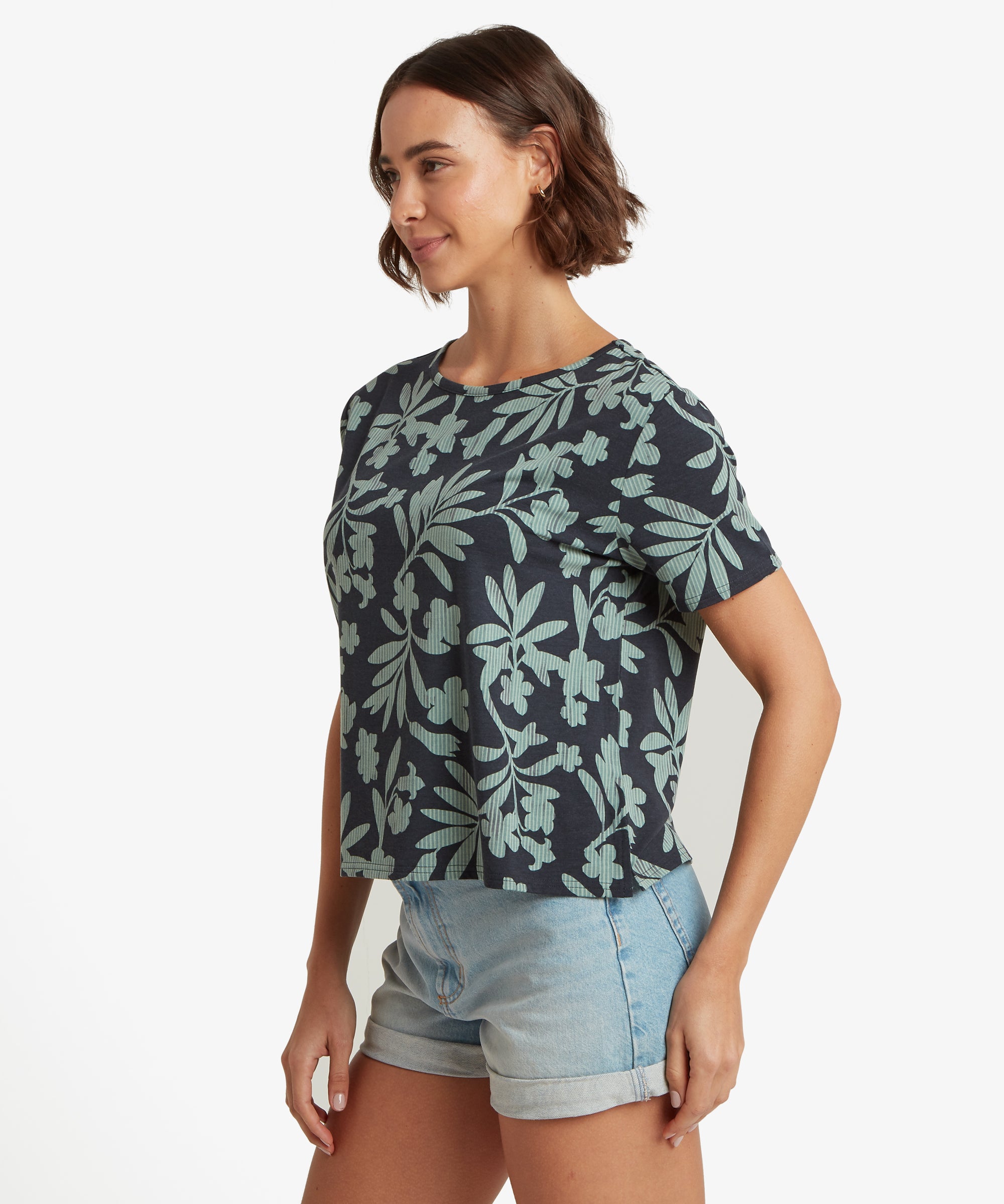 Seitenansicht eines marineblauen Kurzarm-T-Shirts mit hellgrŸnem Blumenmuster, kombiniert mit hellblauen Jeansshorts mit umgeschlagenem Saum.
