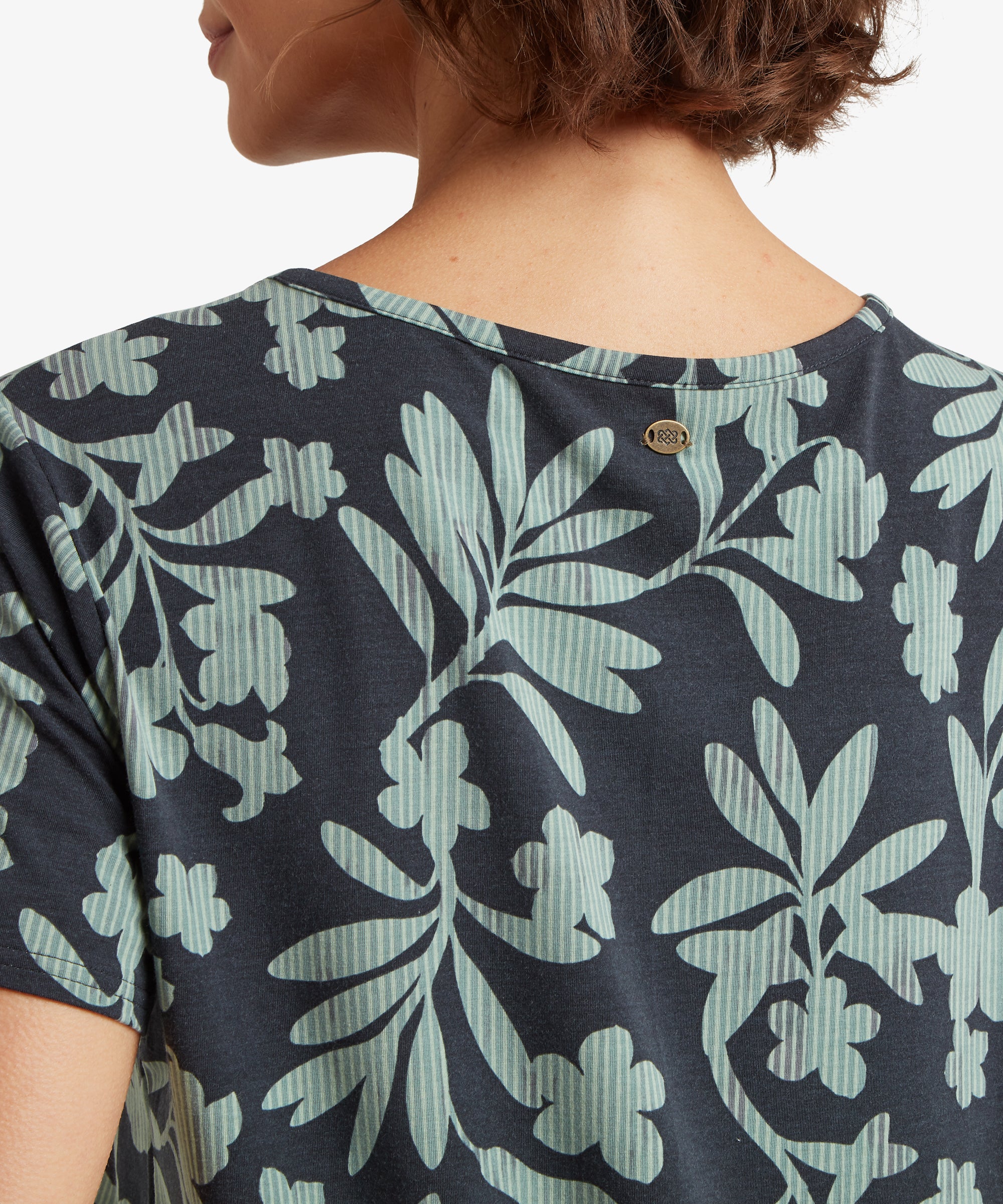 RŸckansicht eines marineblauen T-Shirts mit botanischem Print, kombiniert mit hellblauen Jeansshorts mit gerolltem Saum, die den lockeren Fall des Shirts zeigen.