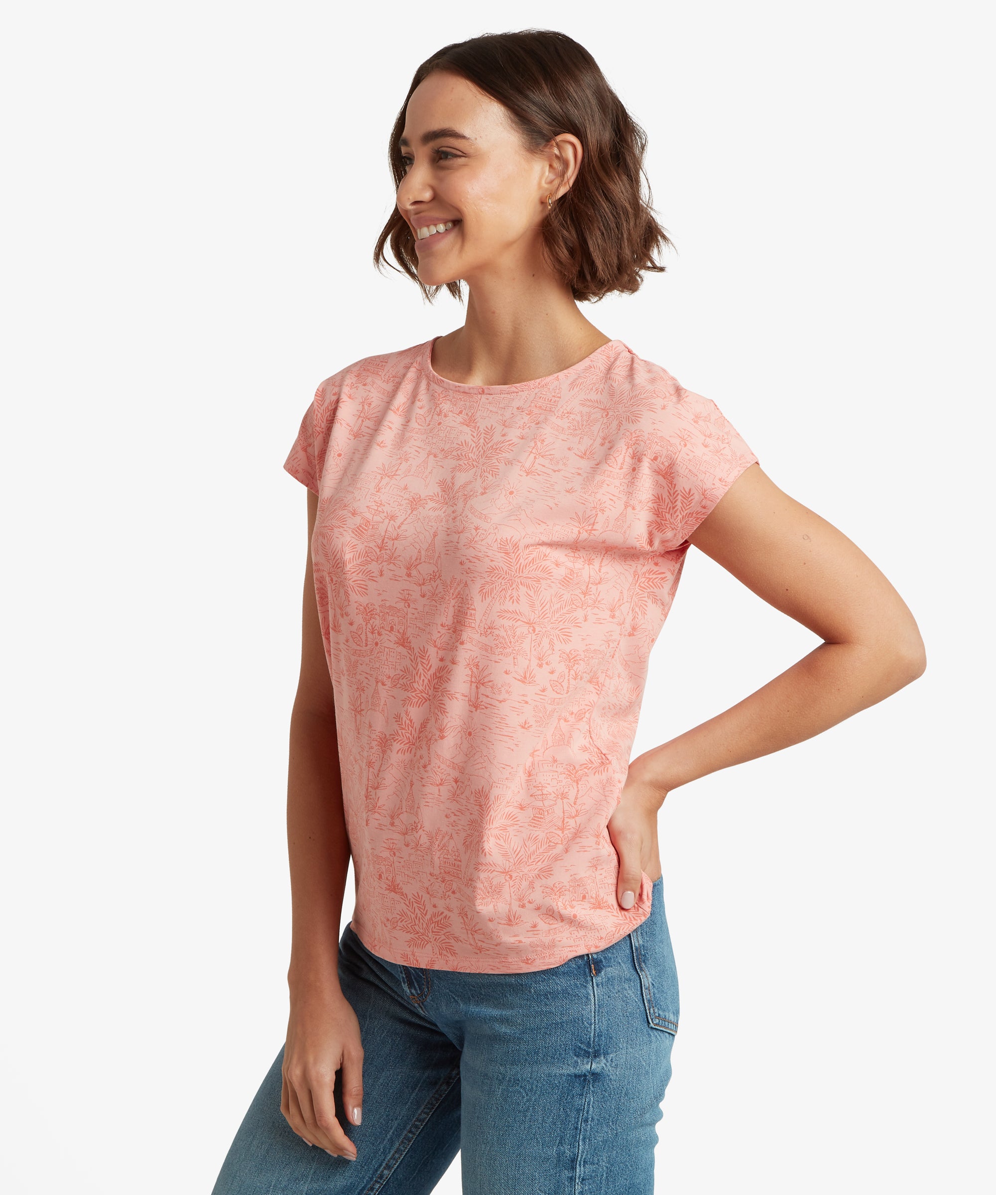 Side view of a pale pink printed T‑shirt worn with mid‑wash blue jeans, showing its relaxed fit and short sleeves.