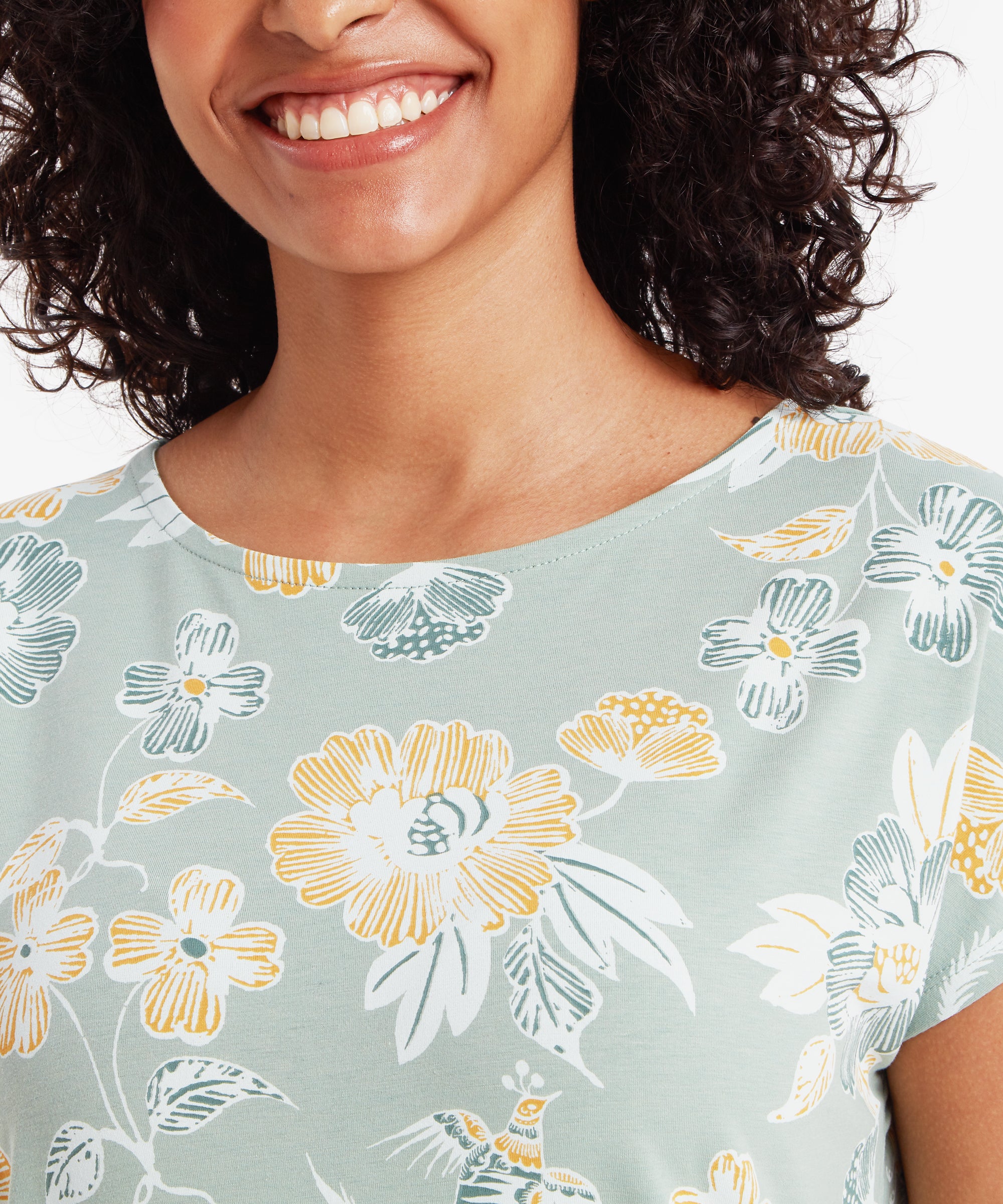 Close‑up of the chest area of a mint green floral T‑shirt, showing detailed printed flowers and leaves.