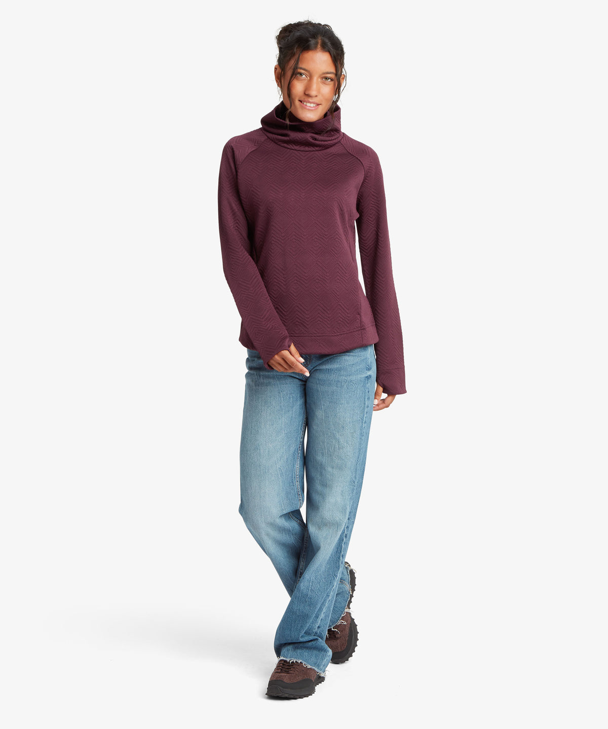 A woman modeling a long-sleeve cowl-neck sweater in a deep plum purple color.