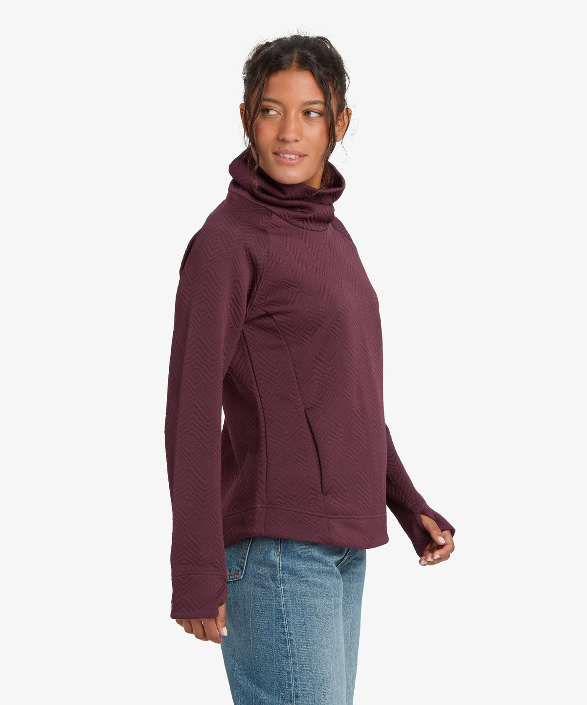 A woman wearing a ribbed, long-sleeve turtleneck sweater in a deep plum purple color.