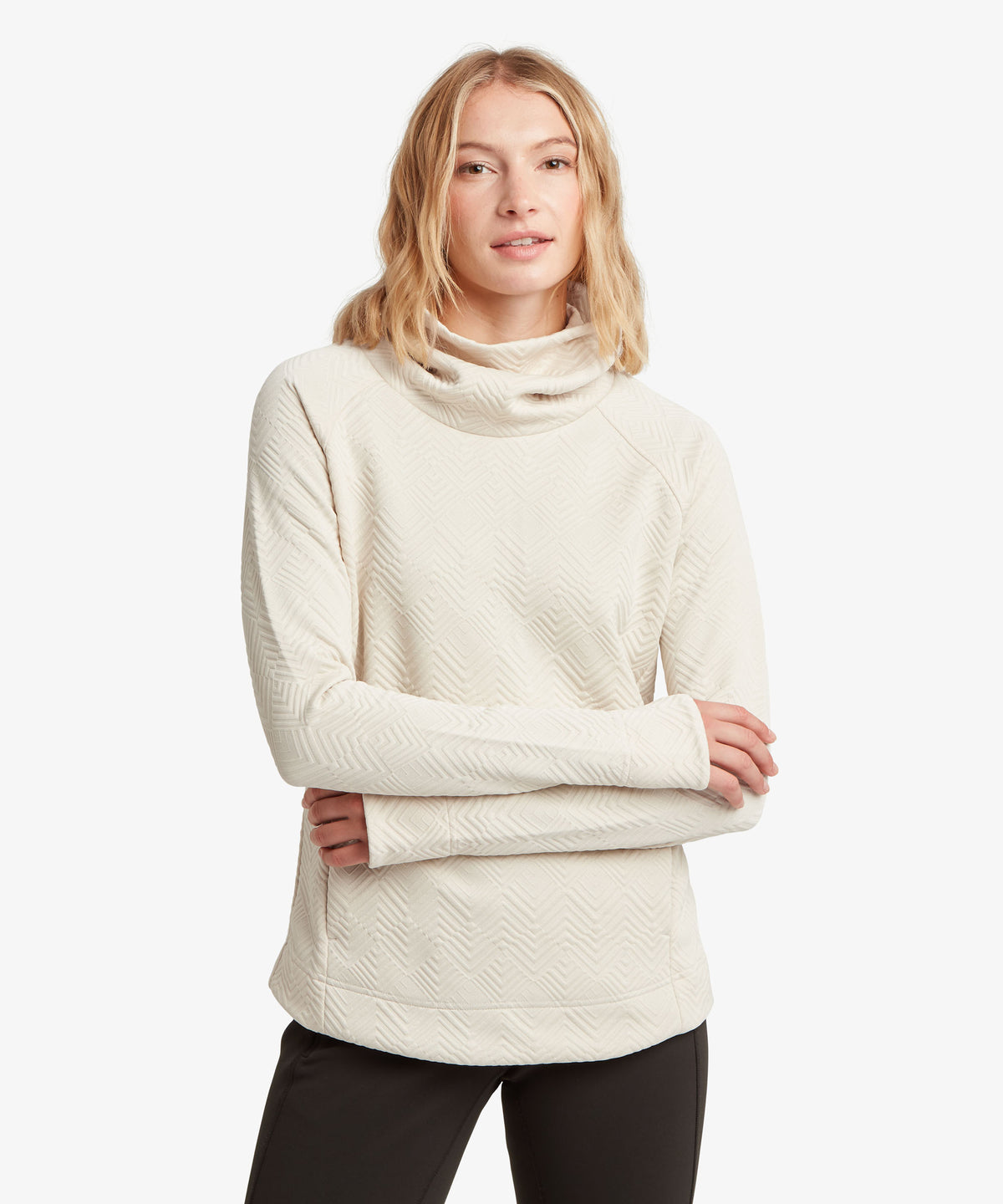 A woman modeling a cream-colored, cowl-neck long-sleeve sweater against a white background.