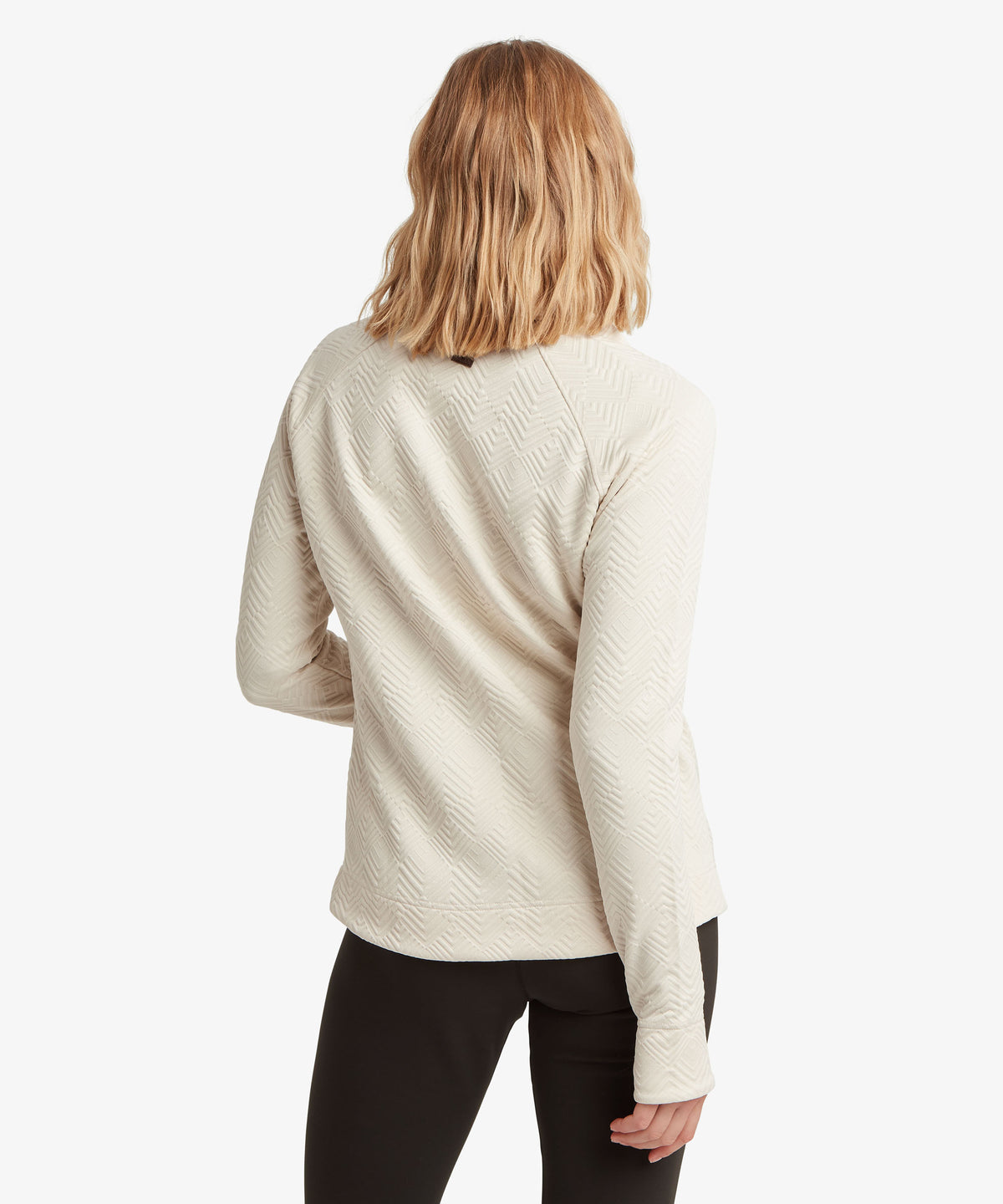 A woman viewed from the back wearing a cream-colored textured knit sweater.
