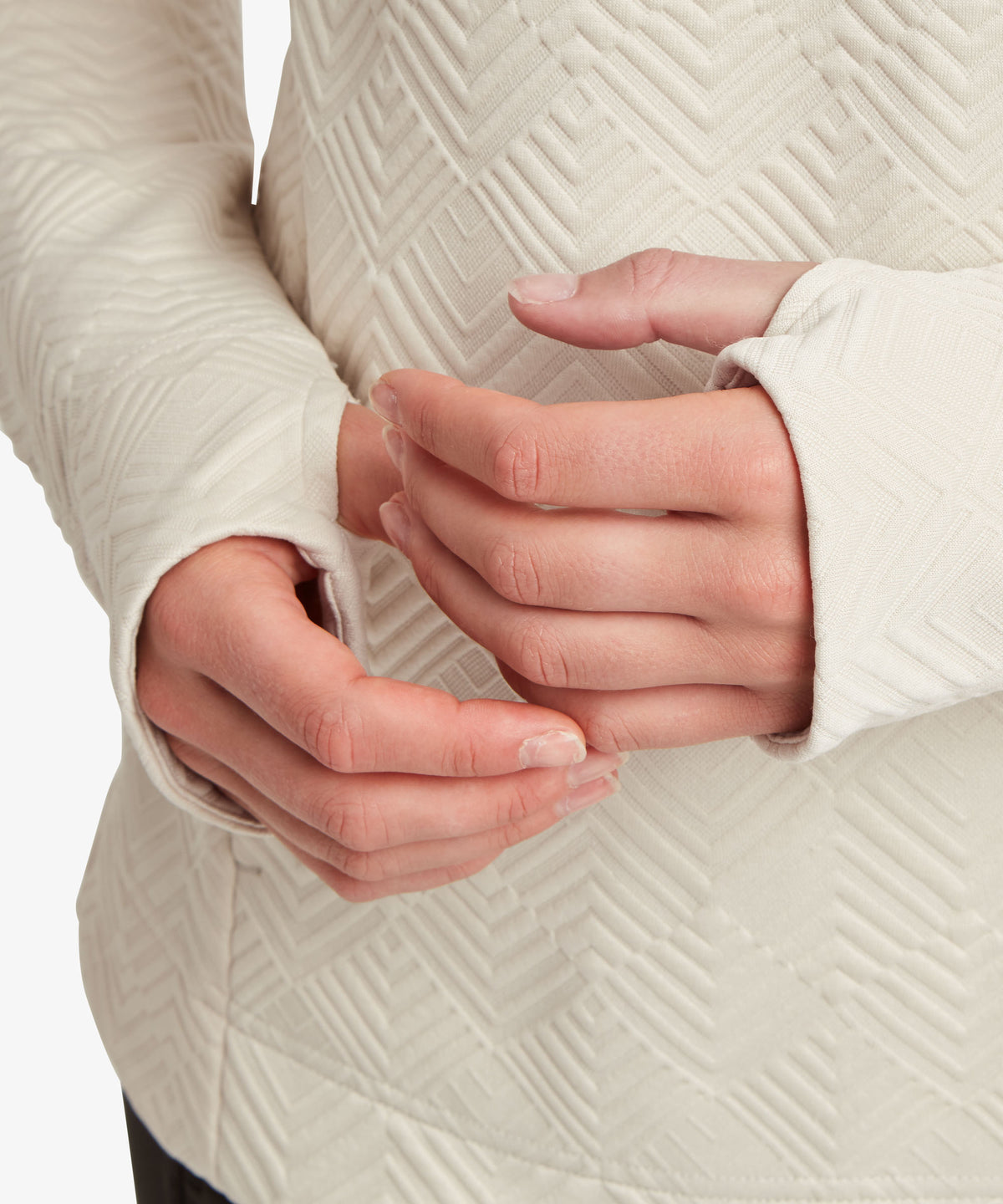 Close-up of a person wearing a cream-colored sweater showing the hands.