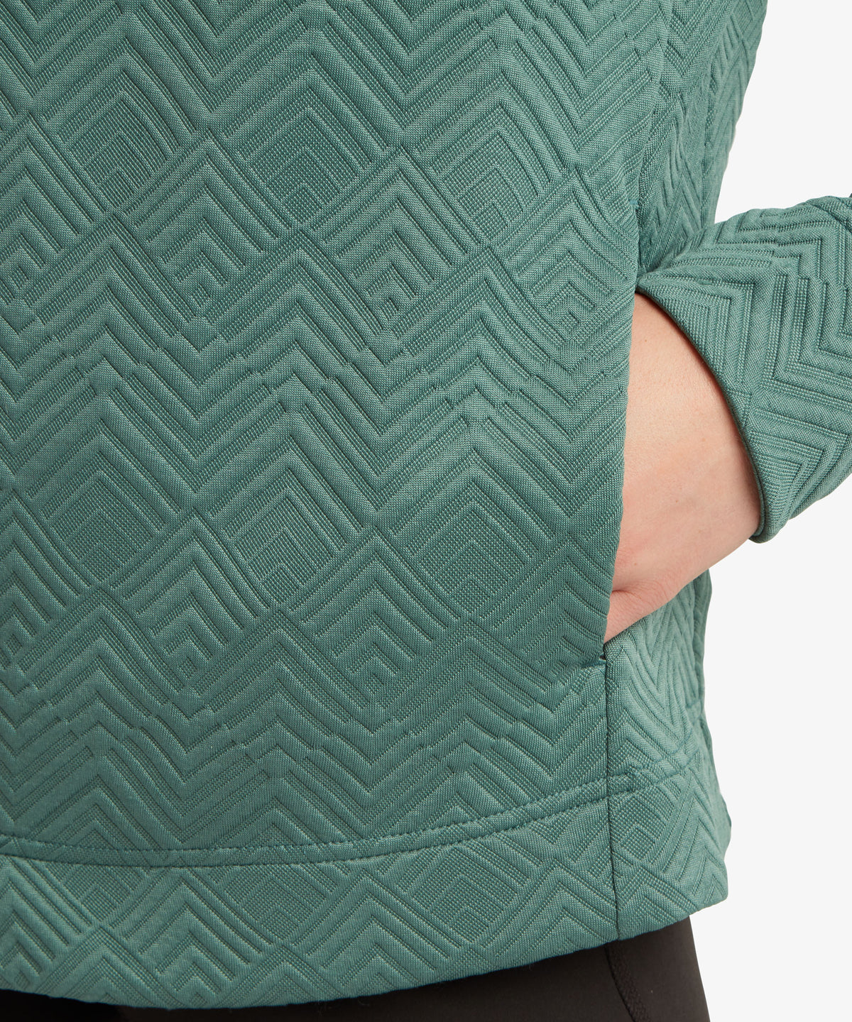 Close-up of a textured sage green sweater with a geometric embossed pattern.