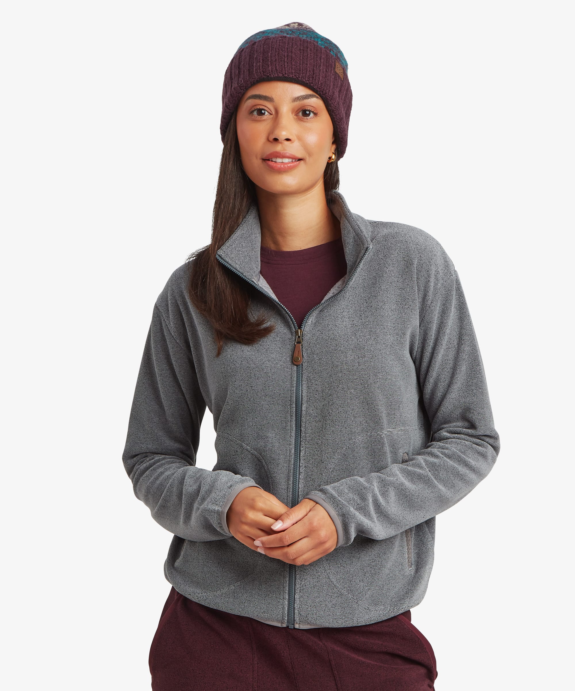 Front view of a woman wearing the Sherpa Rolpa Full-Zip Fleece Jacket in grey, styled with burgundy trousers and a knitted beanie. The fleece jacket features a full-length zip, stand collar and hand pockets.