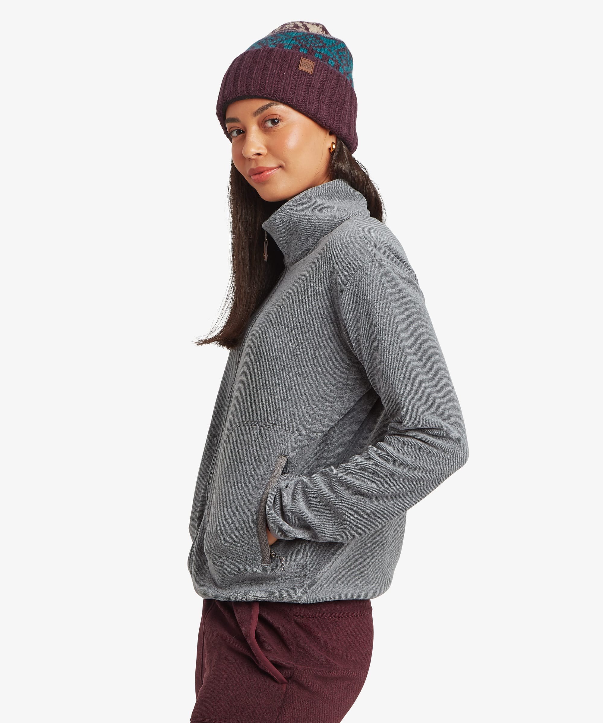 Side profile view of a woman wearing the Sherpa Rolpa Full-Zip Fleece Jacket in grey. The image showcases the stand collar, full-zip closure and relaxed silhouette.