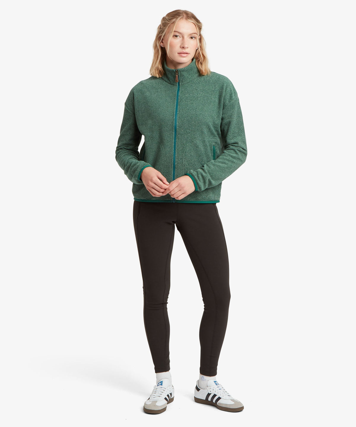 A female model wearing the Sherpa Adventure Gear Rolpa Full Zip fleece in green.