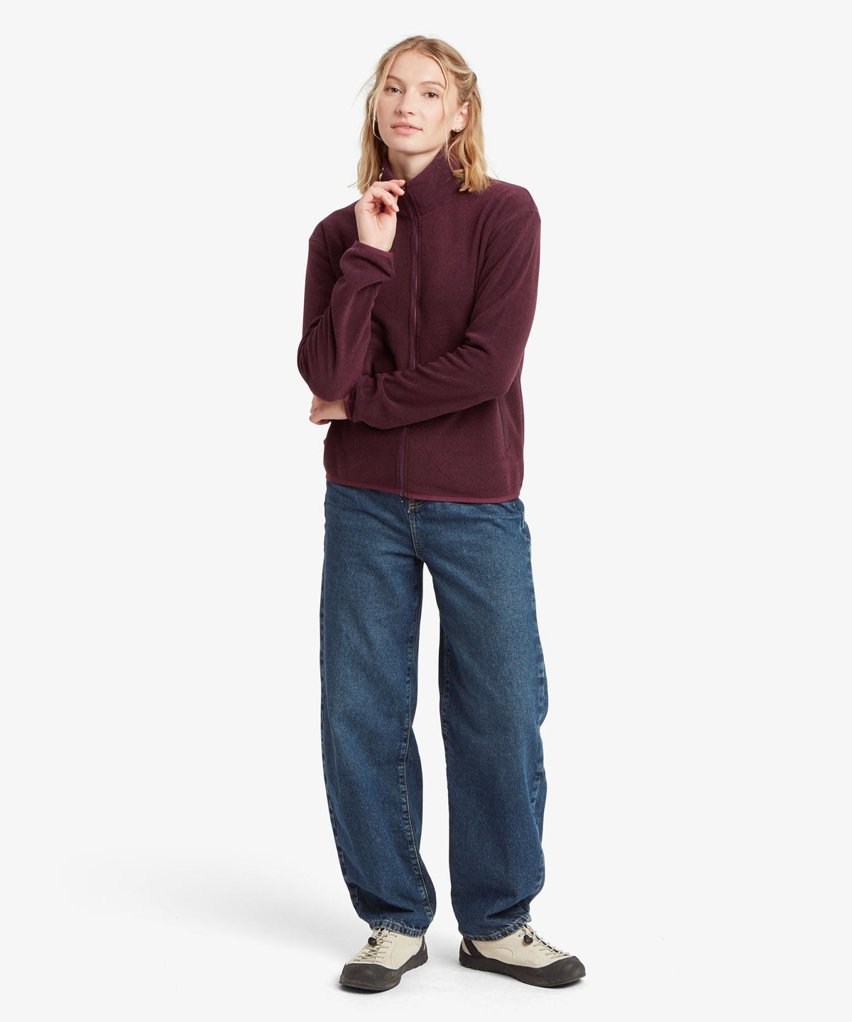 A female model wearing the Sherpa Adventure Gear Rolpa Full Zip fleece in purple.