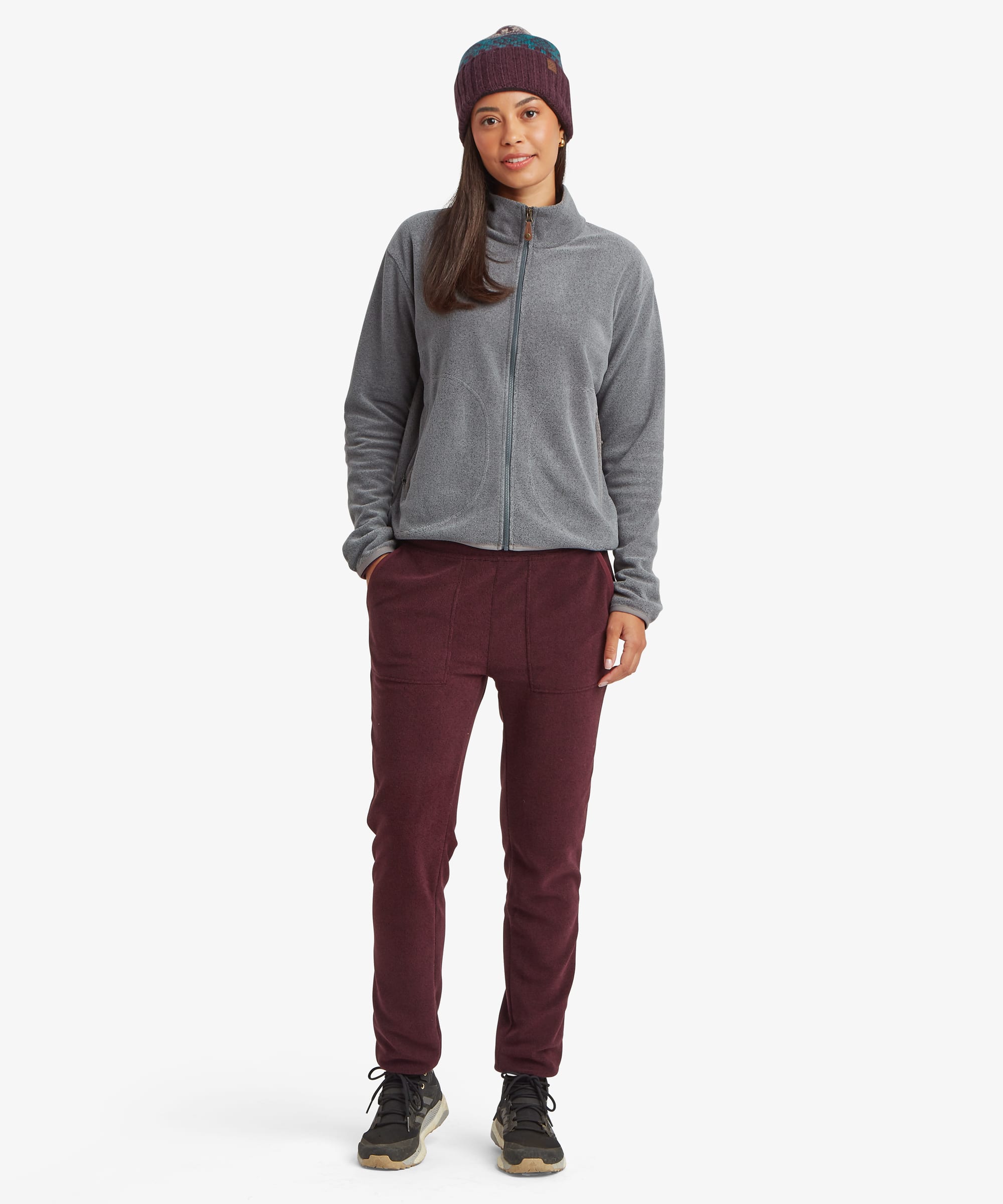 Full-body view of a woman wearing the Sherpa Rolpa Jogger in burgundy red. The image highlights the tapered fit, ankle cuffs and casual outdoor-inspired styling.
