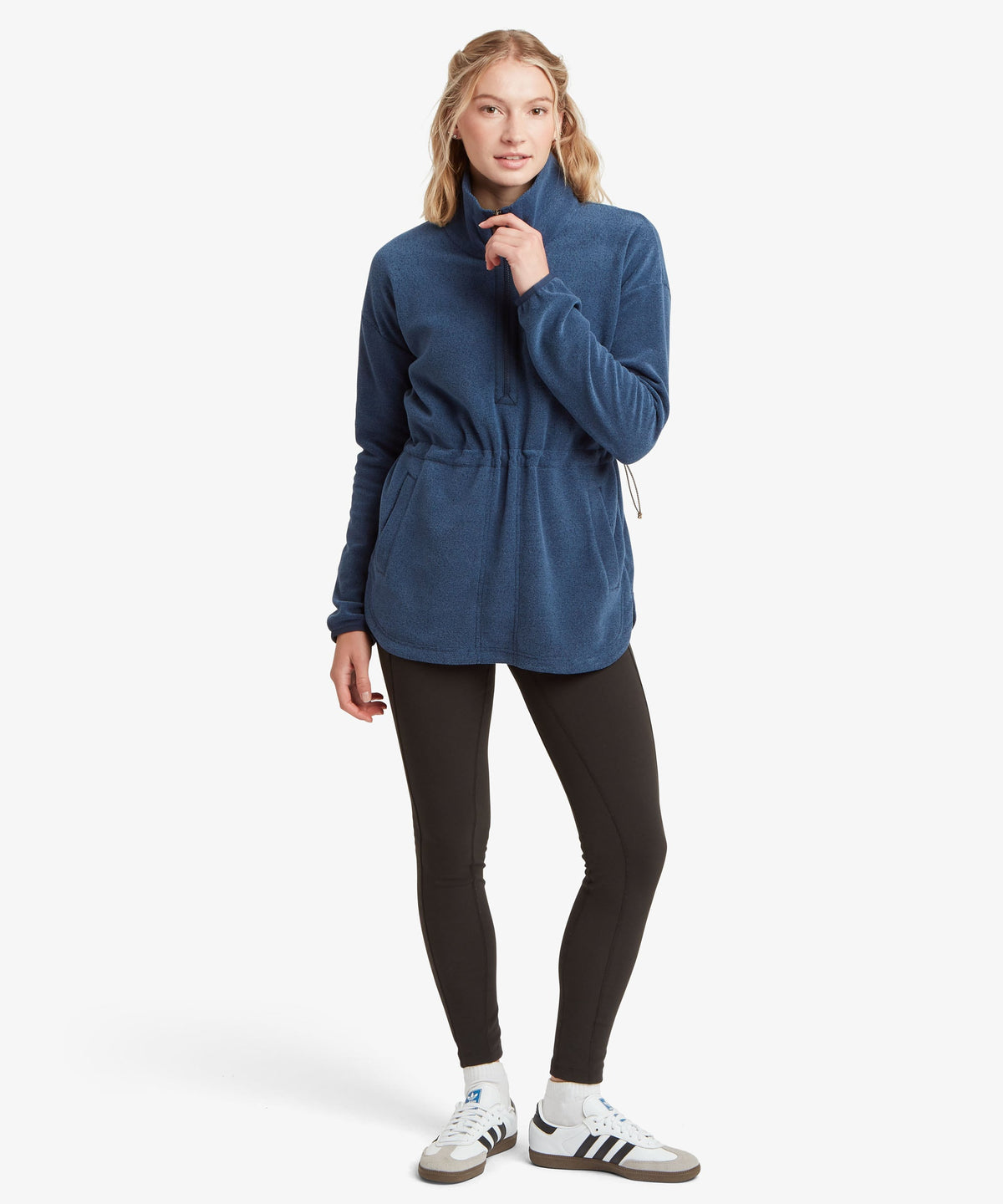 A female model wearing the Sherpa Adventure Gear navy Rolpa Pop-Over fleece with black leggings.