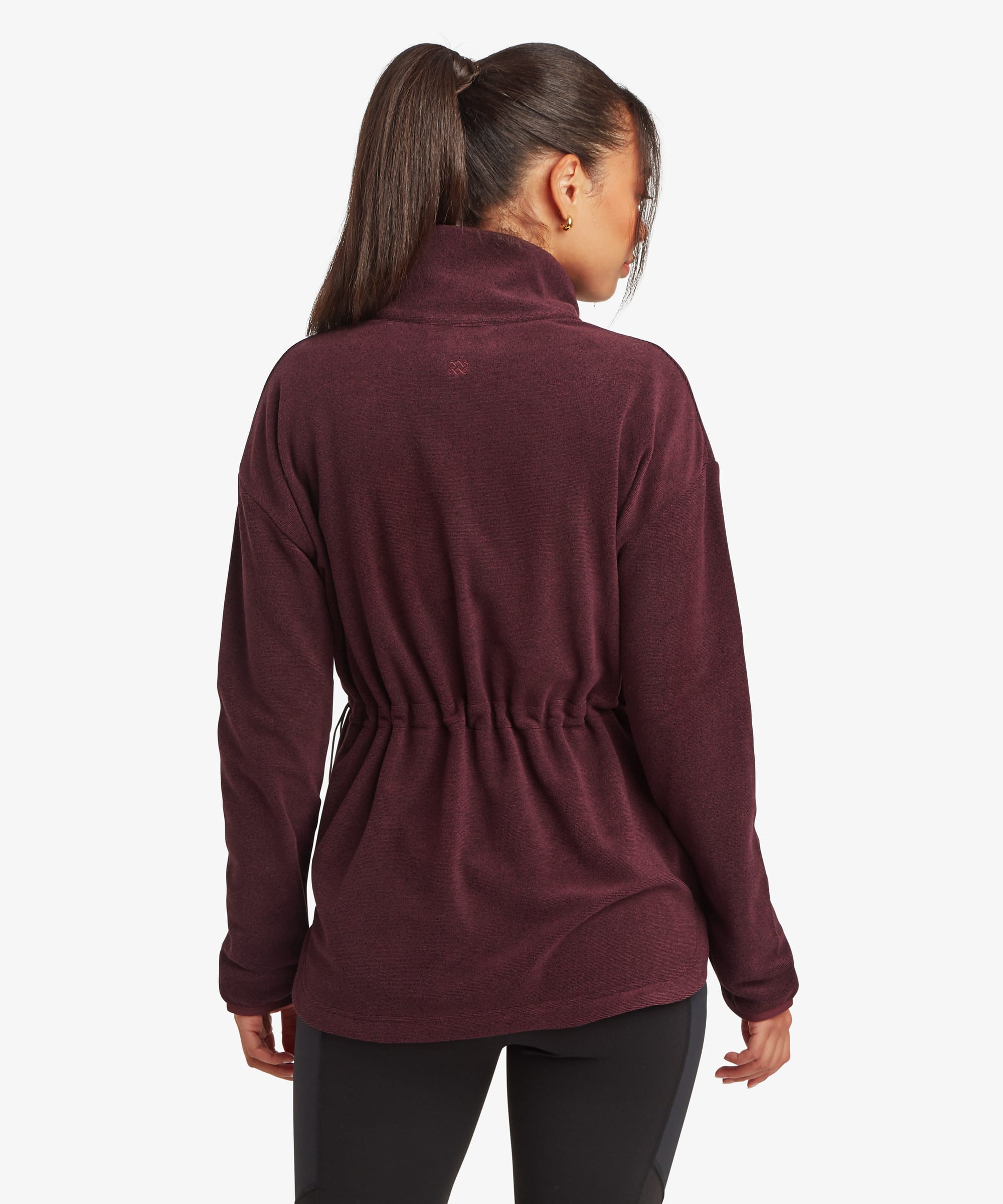 Rear view of a woman wearing a burgundy Sherpa Rolpa Pop Over fleece. The image showcases the clean back design, relaxed silhouette and curved hemline against a white studio background.