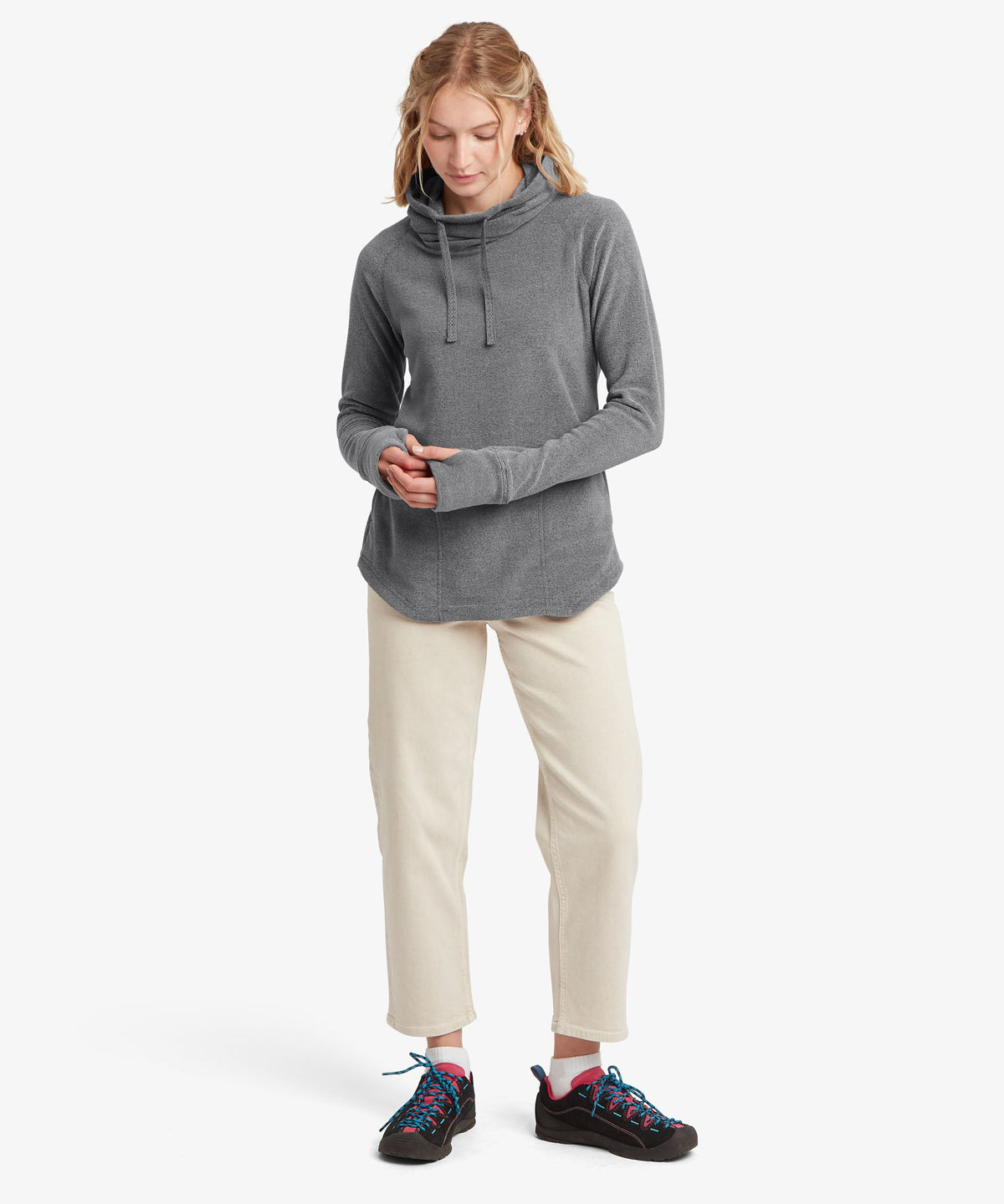 A female model wearing the Sherpa Adventure Gear grey Rolpa Pullover with cream trousers.