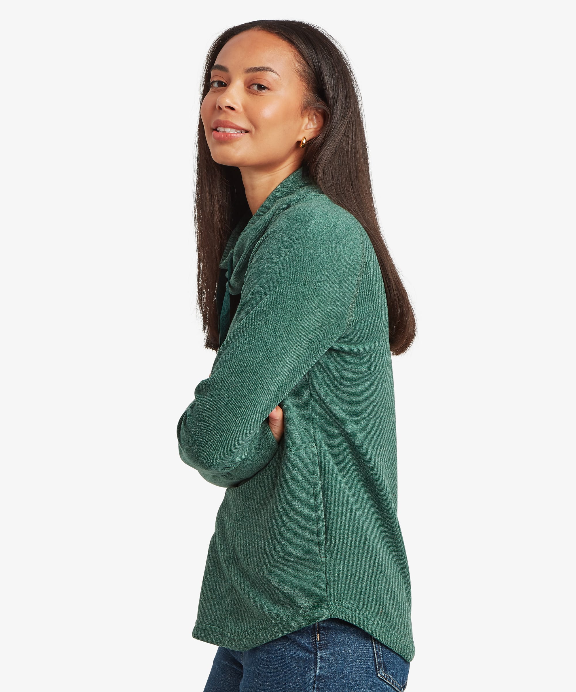 Three-quarter side view of a woman wearing a teal green Sherpa Rolpa Pullover. The image showcases the relaxed fit, curved hem and soft fleece construction against a white studio background.