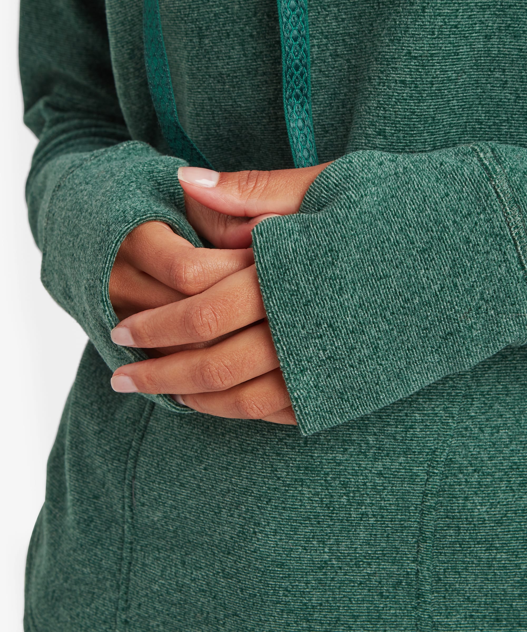 Close-up detail of the teal green Sherpa Rolpa Pullover showing the sleeve cuffs and front pouch pocket area. The textured fleece fabric and relaxed fit are clearly visible.