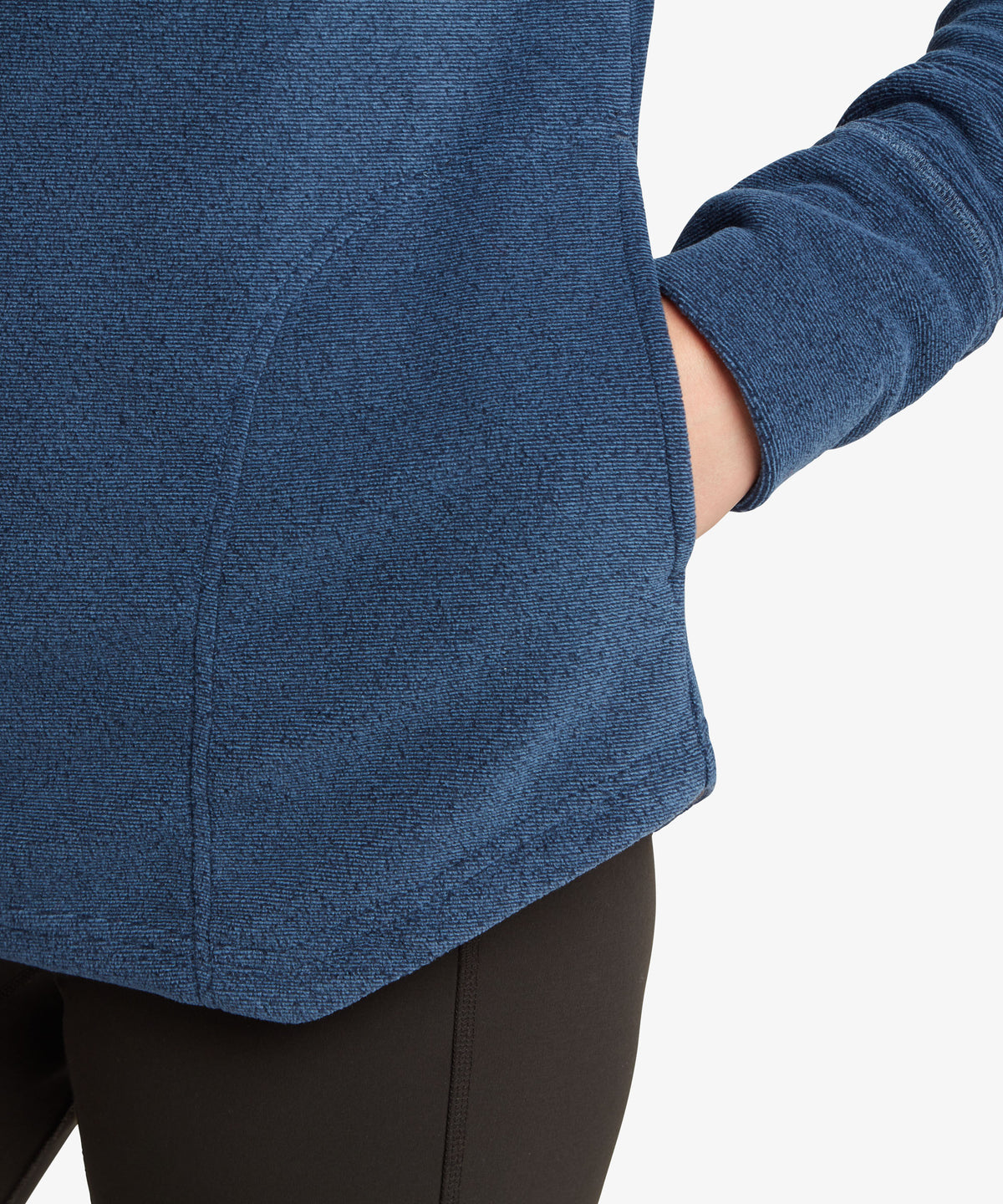 Close-up of hand in side pocket of navy pullover, hip-length hem visible