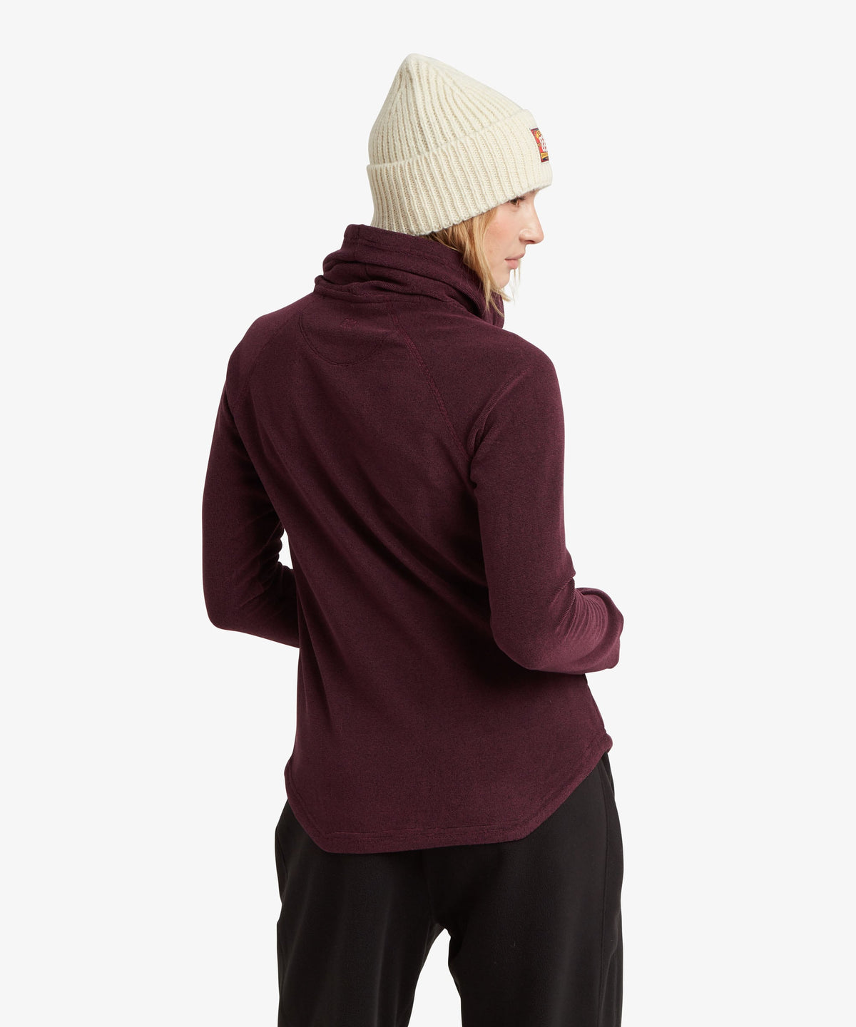 Rear view of a woman looking over her shoulder wearing a deep purple fleece pullover.