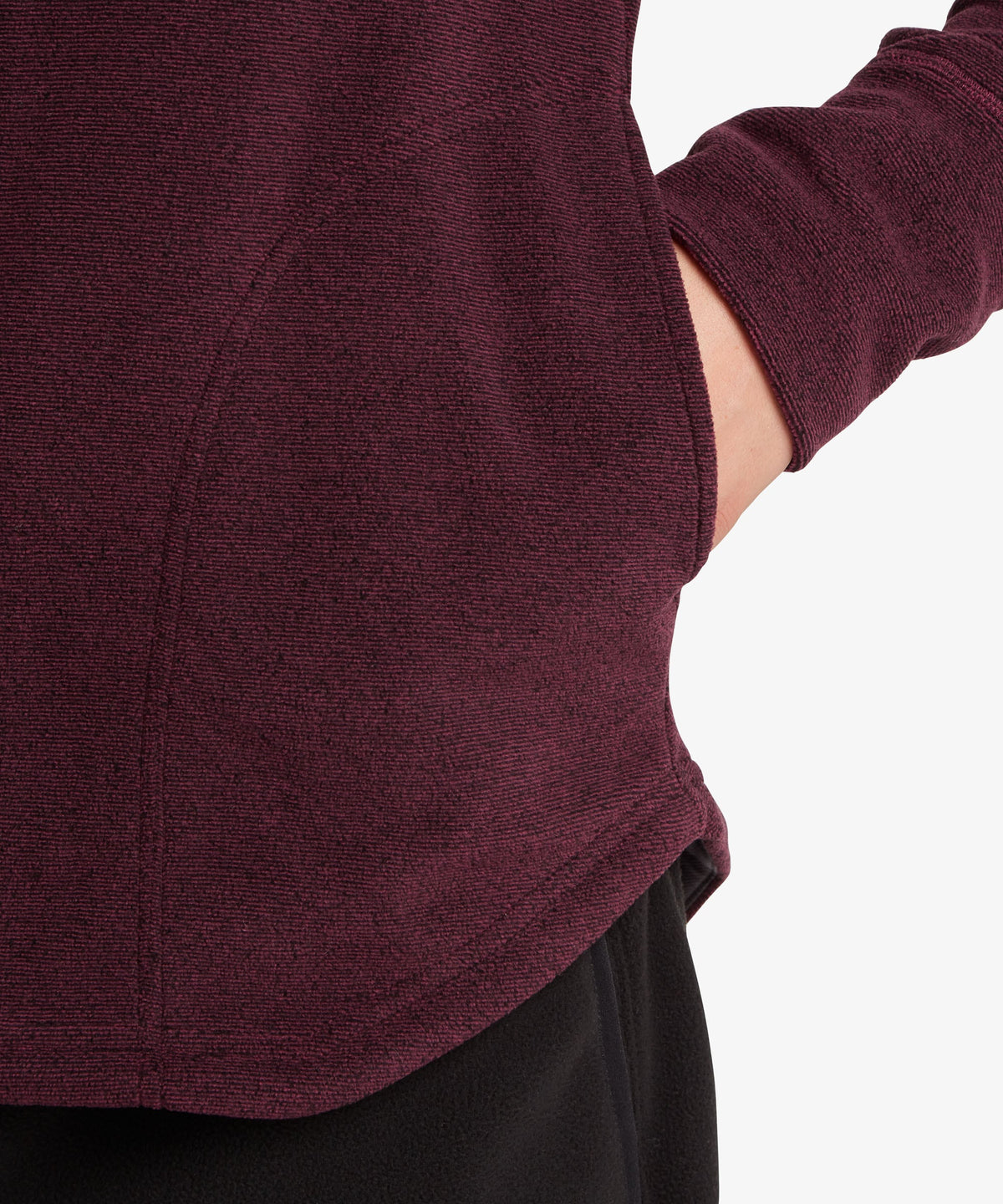 Close-up shot of a hand resting in the side pocket of a dark purple fleece sweater