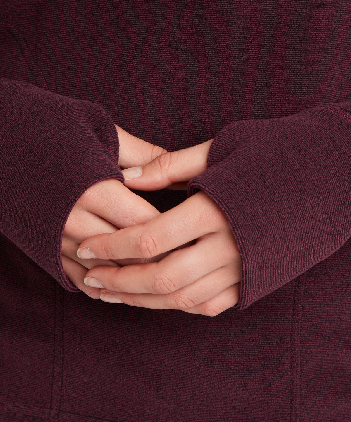 Close-up view of hands clasped together wearing a dark purple fleece long-sleeve top