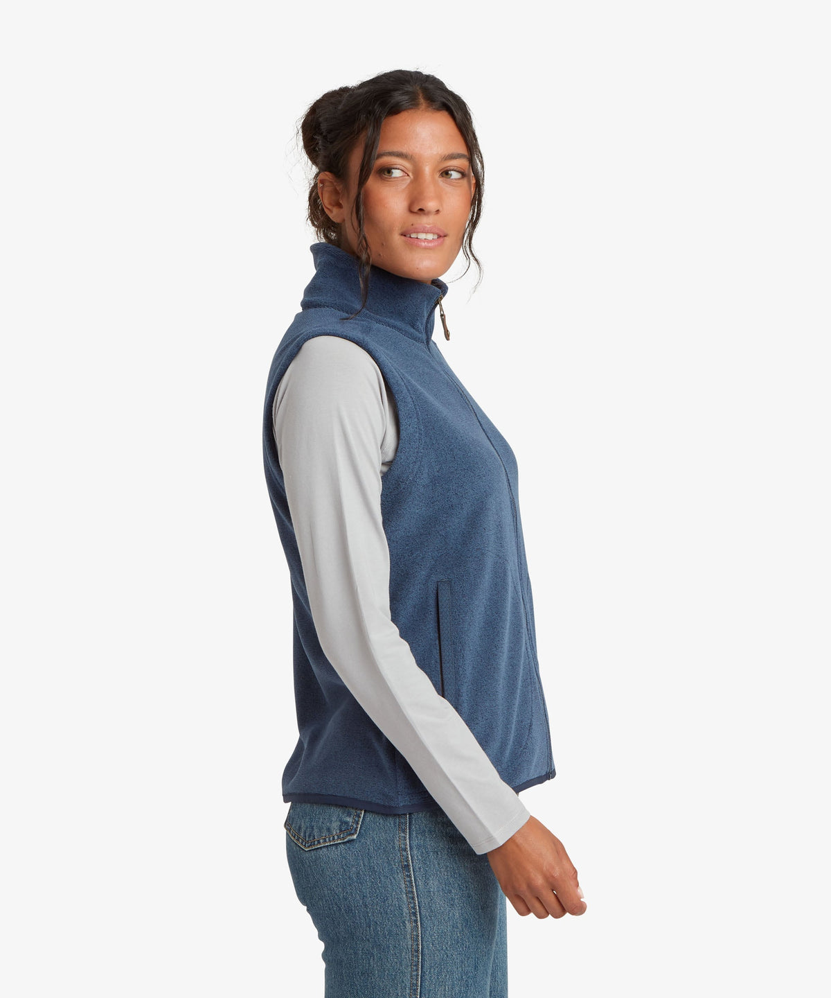 A woman modeling a sleeveless blue fleece vest over a light gray long-sleeve shirt.