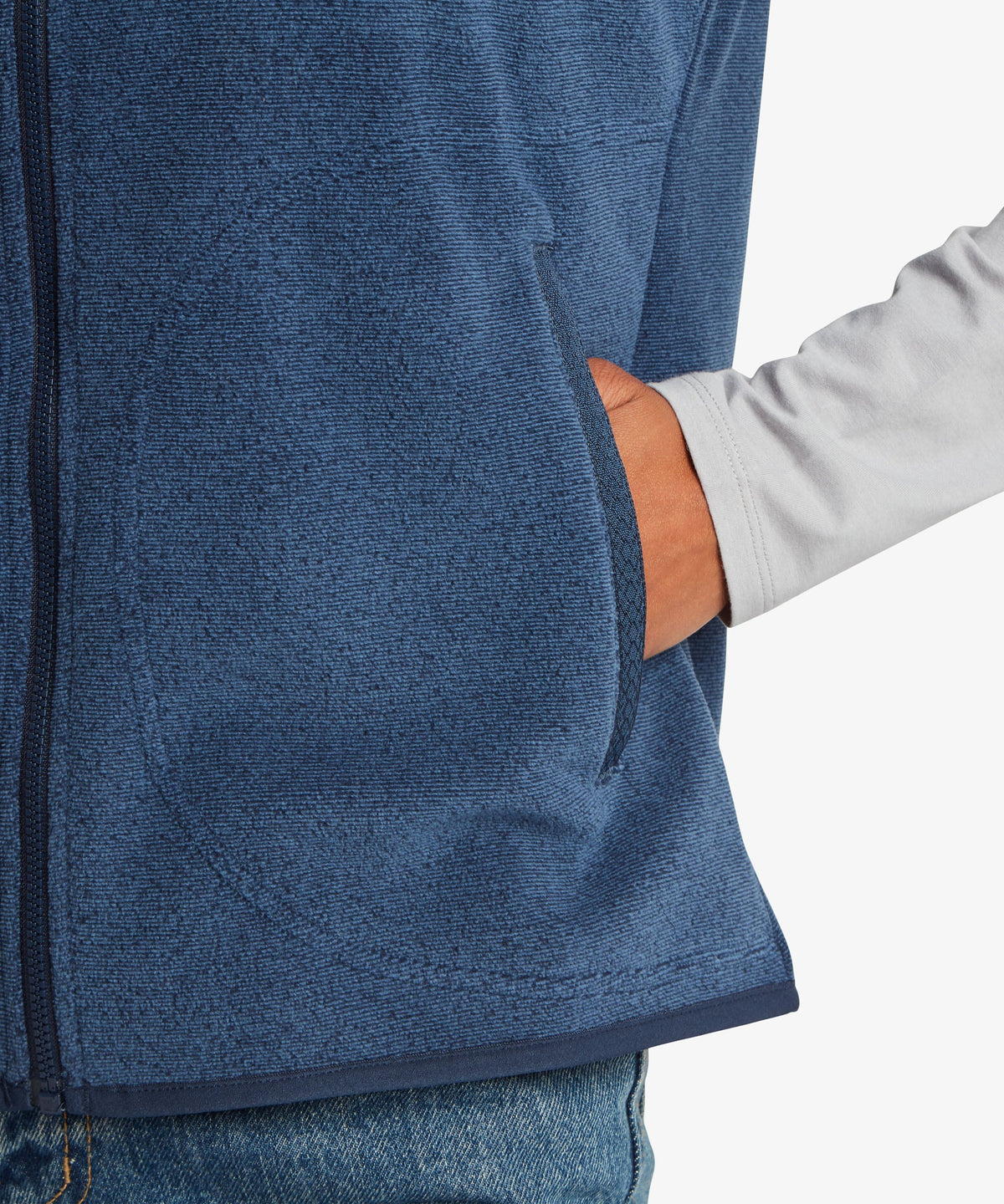 Close-up of a person wearing a heathered blue zip-front fleece vest with a side pocket.