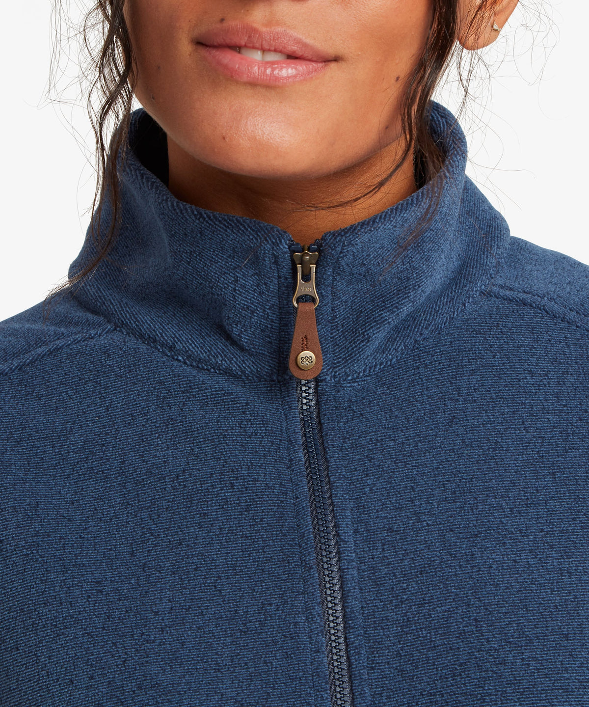 Close-up of a person wearing a heathered blue quarter-zip fleece jacket with a brown faux leather.