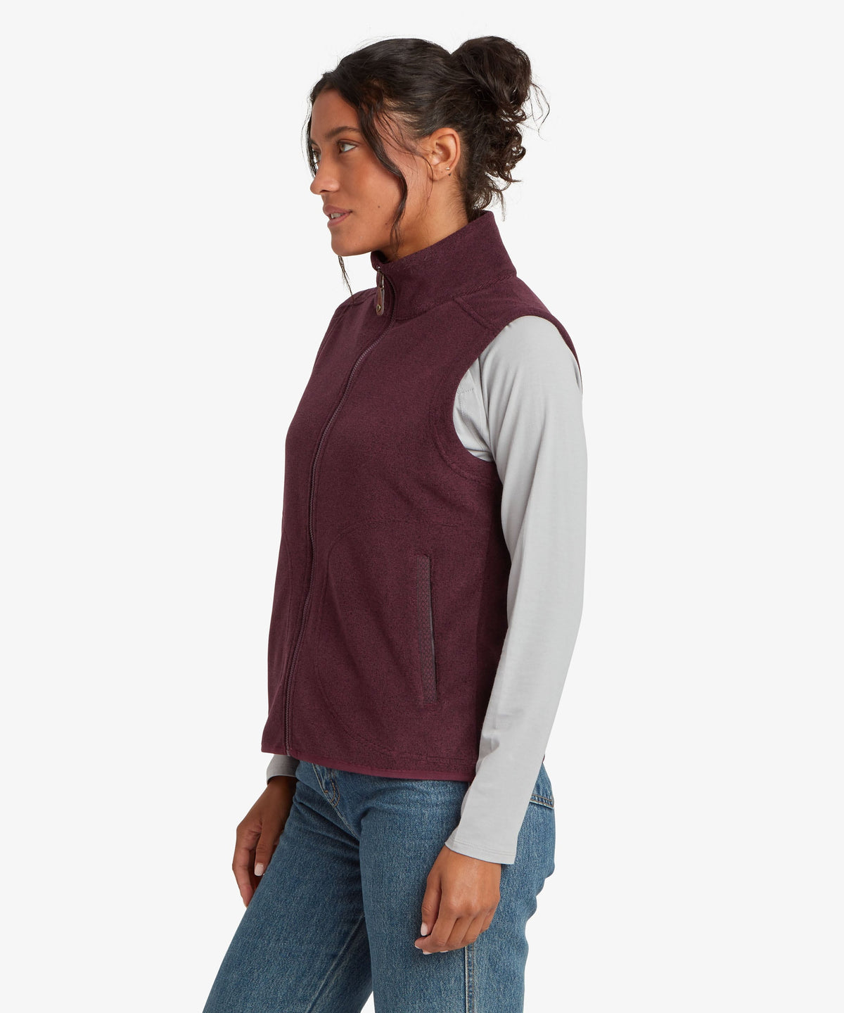 A woman shown in side profile wearing a sleeveless zip-front fleece vest in deep burgundy.
