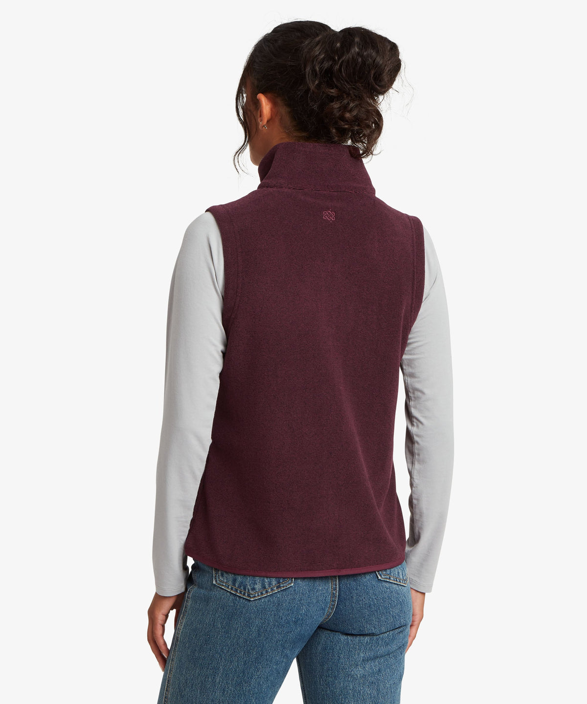 A female model wearing the Sherpa Adventure Gear purple Rolpa Vest over a long-sleeve top.
