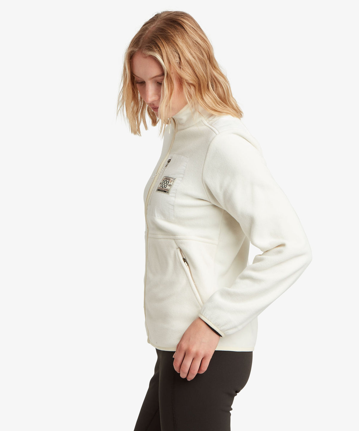 A female model wearing the Sherpa Adventure Gear white Sanu Full-Zip fleece.