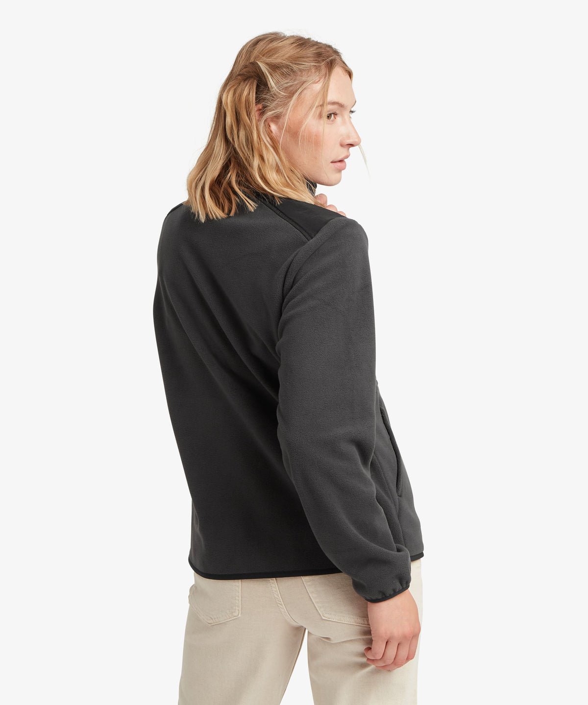 A female model wearing the Sherpa Adventure Gear black Sanu Full-Zip fleece.