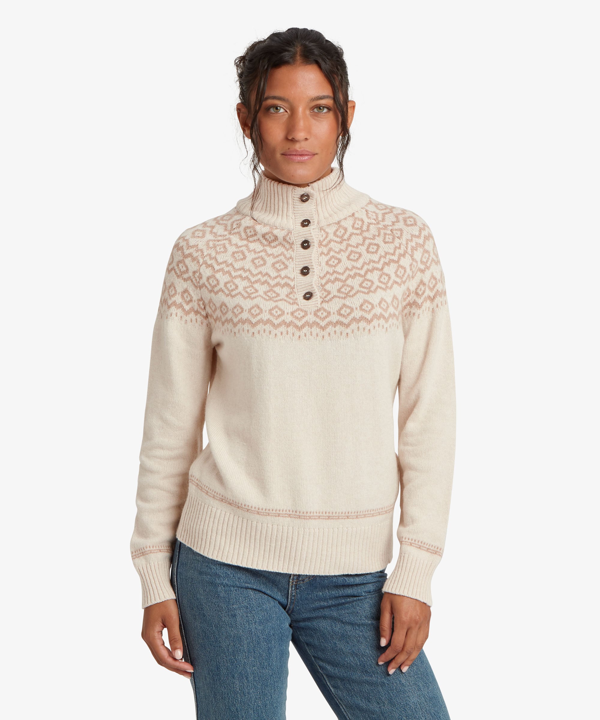 A female model wearing the Sherpa Adventure Gear beige Shanta Sweater with blue jeans, shown full length in a studio setting. The sweater features a high buttoned collar, long sleeves and a patterned yoke across the chest and shoulders, with a relaxed fit through the body.