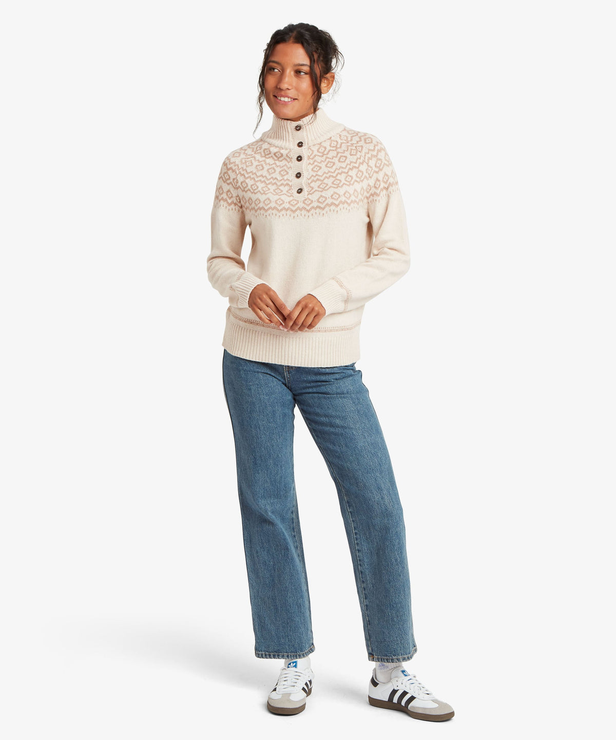 A female model wearing the Sherpa Adventure Gear beige Shanta Sweater with blue jeans.