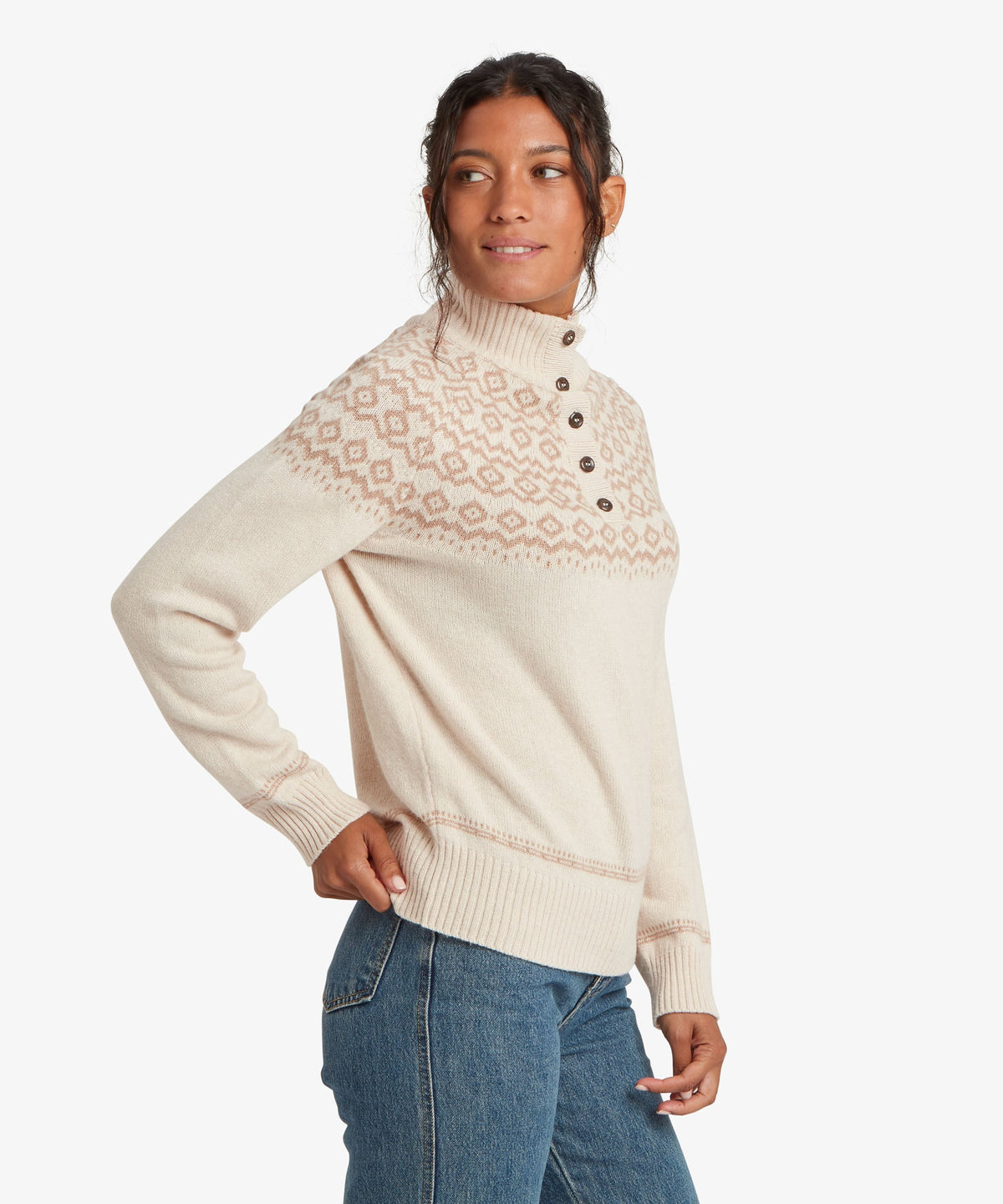 A female model wearing the Sherpa Adventure Gear beige Shanta Sweater with blue jeans.