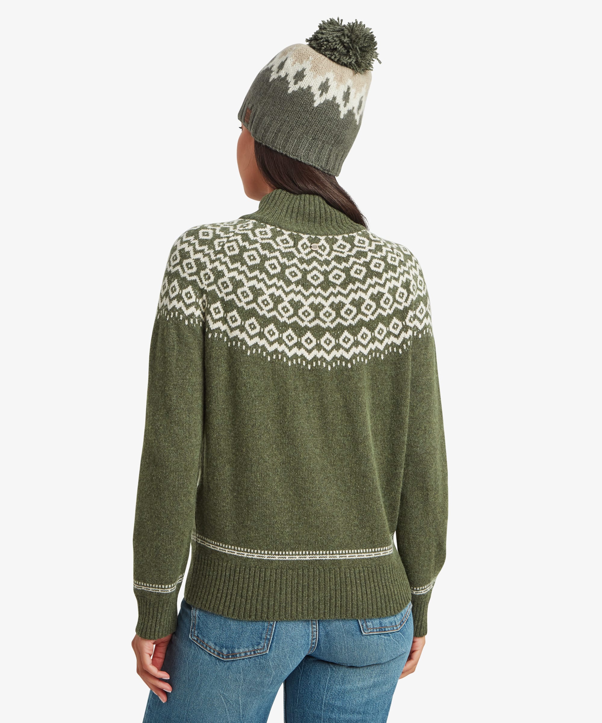 Rear studio view of a woman wearing an olive-green knit sweater featuring a patterned yoke extending around the upper back. The image highlights the sweater's fit and pattern continuity.