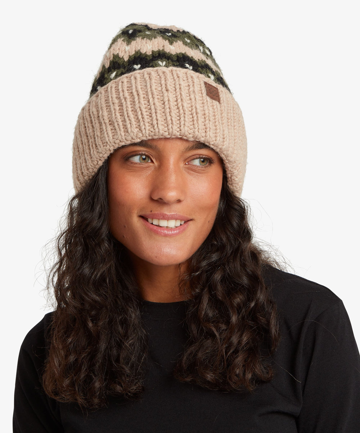 A woman with long, wavy dark hair wearing a beige knit beanie with a dark green.