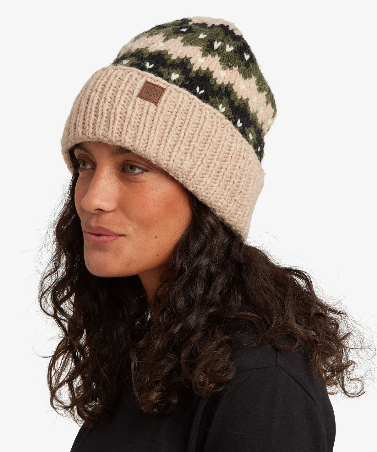 A woman wearing a beige and green patterned knit beanie hat.