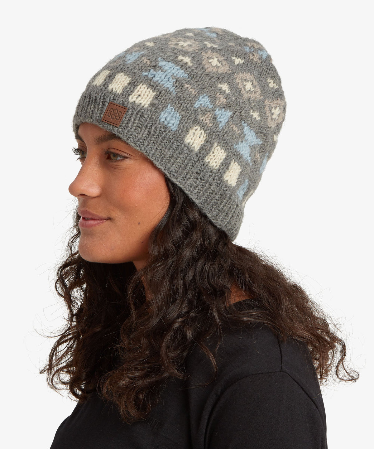A woman in profile wearing a gray knit beanie with a pattern of cream, light blue.