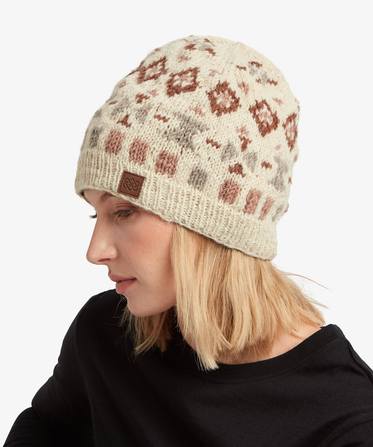 A woman wearing a cream-colored knit beanie with a brown.