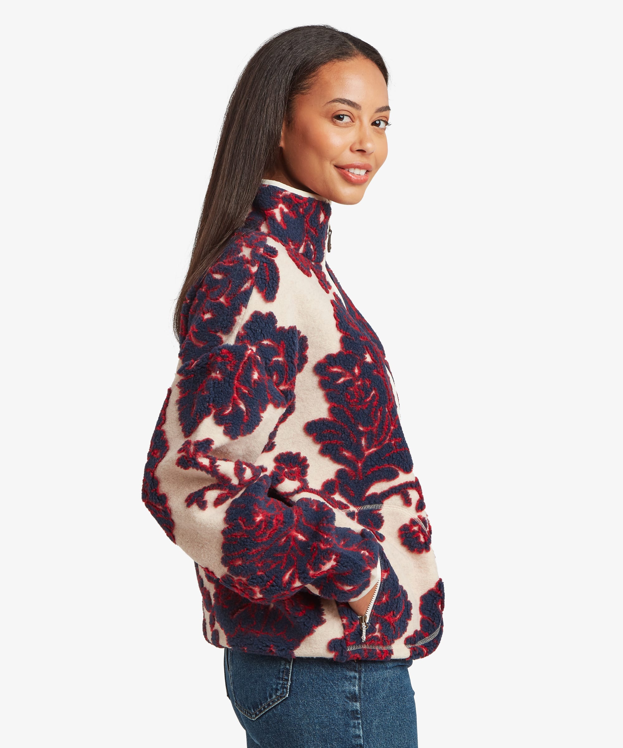 Side-profile studio view of a woman wearing a cream fleece jacket with an oversized burgundy floral pattern. The image showcases the jacket's shape through the body and sleeves.