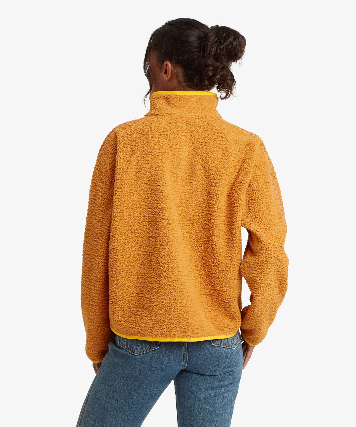 A woman viewed from the back wearing a textured mustard yellow fleece pullover with a high collar.