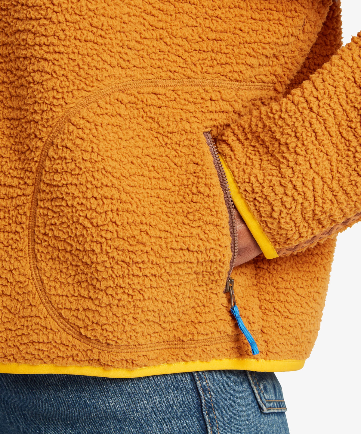 Close-up of a textured fleece jacket in a warm mustard orange color.