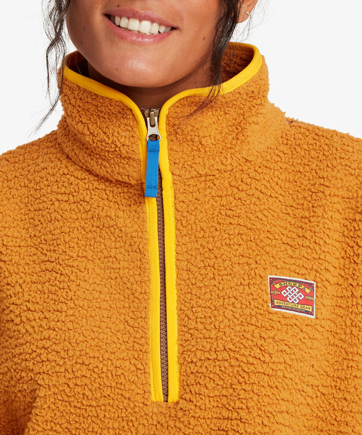 Close-up of a woman wearing a textured fleece quarter-zip pullover in a warm golden yellow-orange.