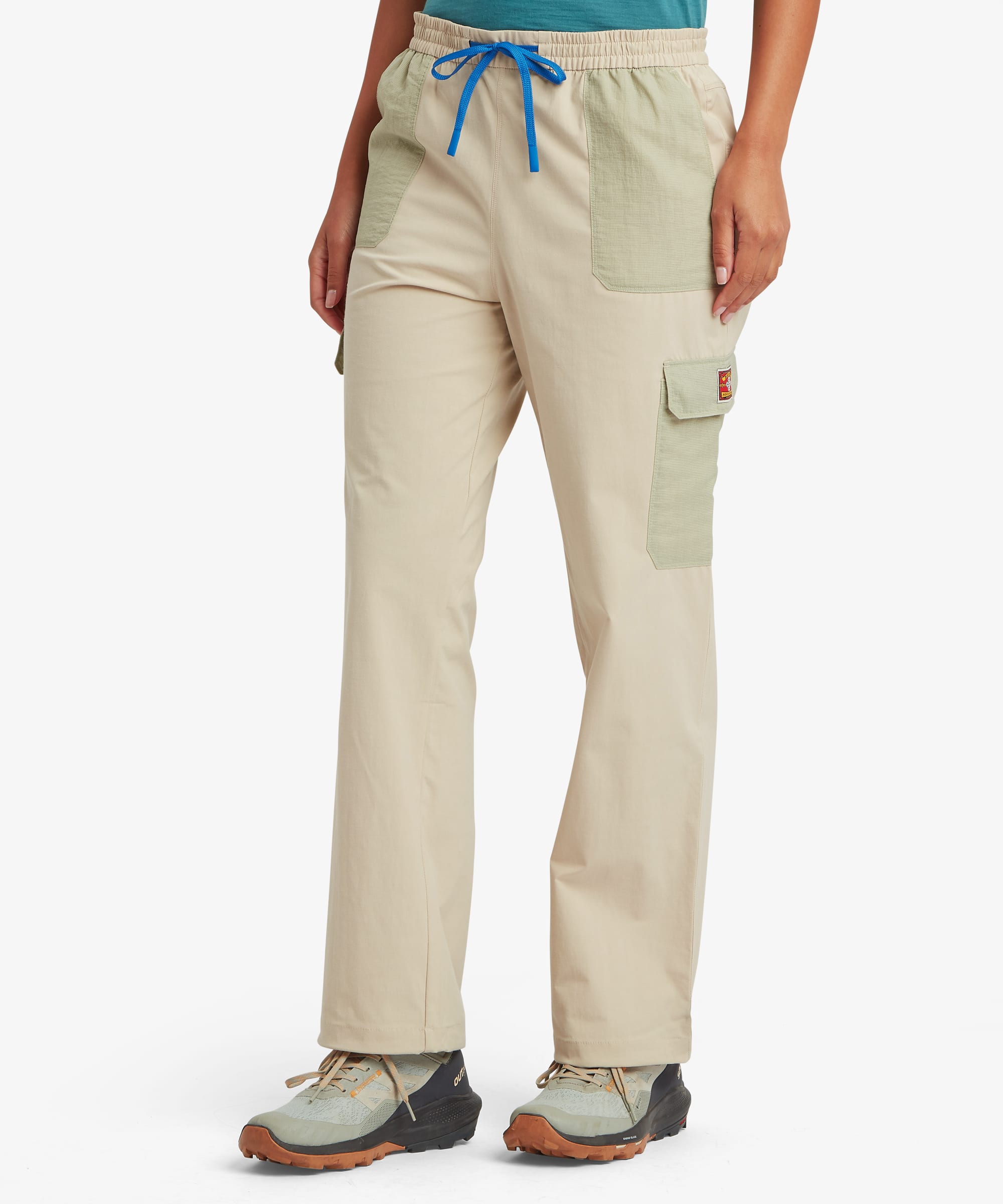 Front view of a woman wearing beige and green cargo pants with a blue drawstring on a white background
