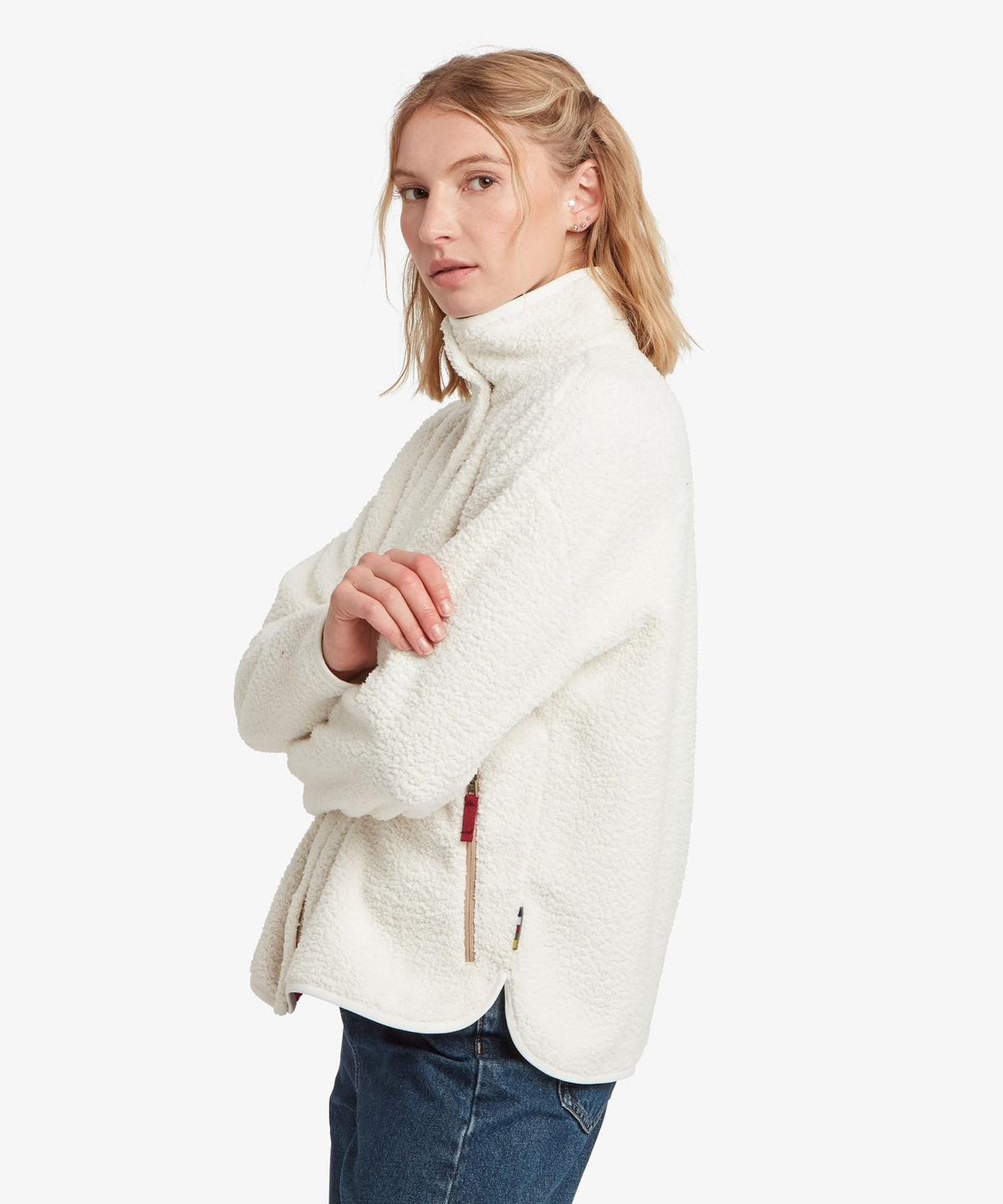 A female model, shown from the side, wearing the white Tarcho Full-Zip Jacket by Sherpa Adventure.