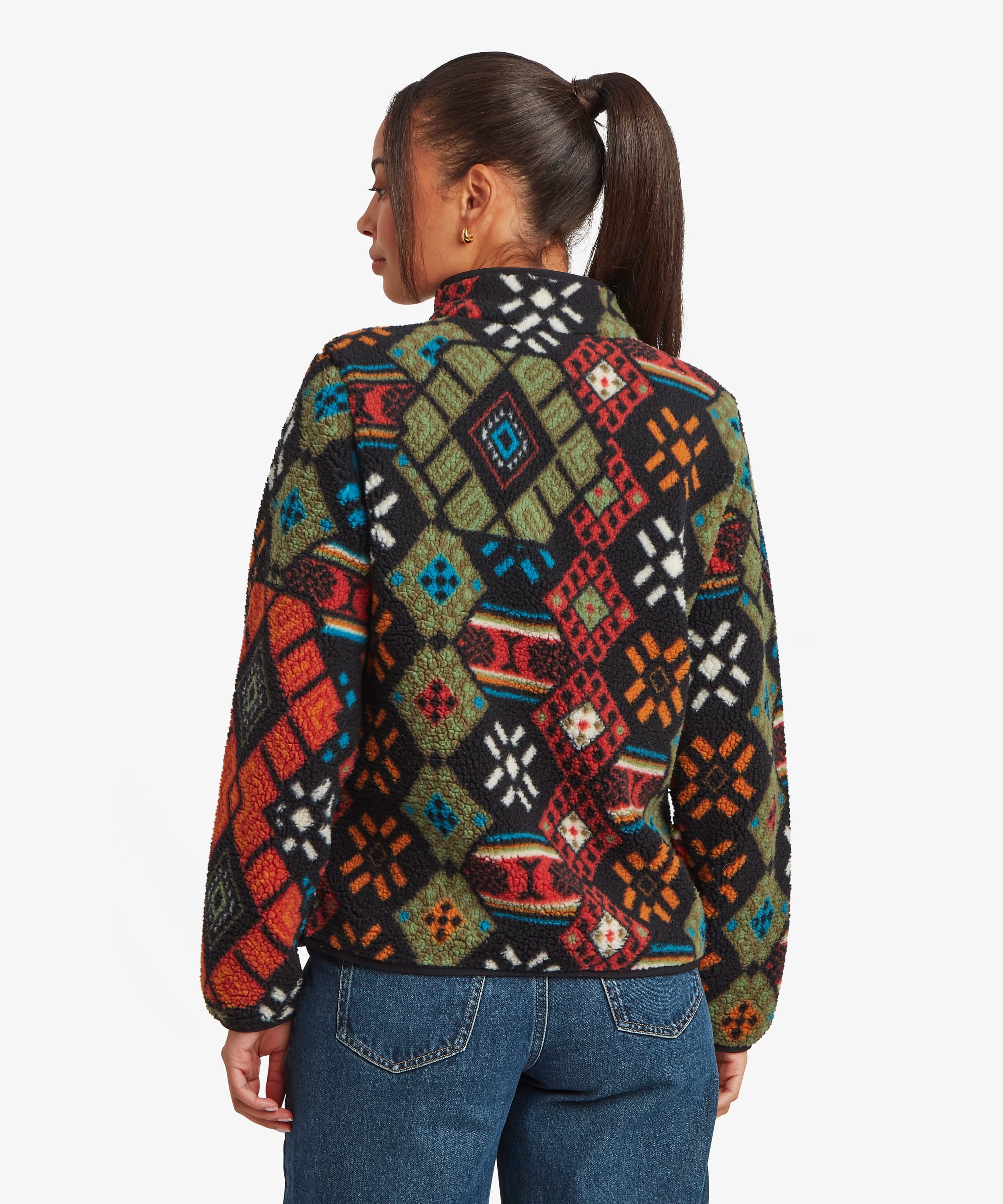 Rear studio view of a woman wearing a black fleece jacket featuring an all-over multicoloured geometric print. The image showcases the pattern across the back panel and sleeves, paired with blue jeans.