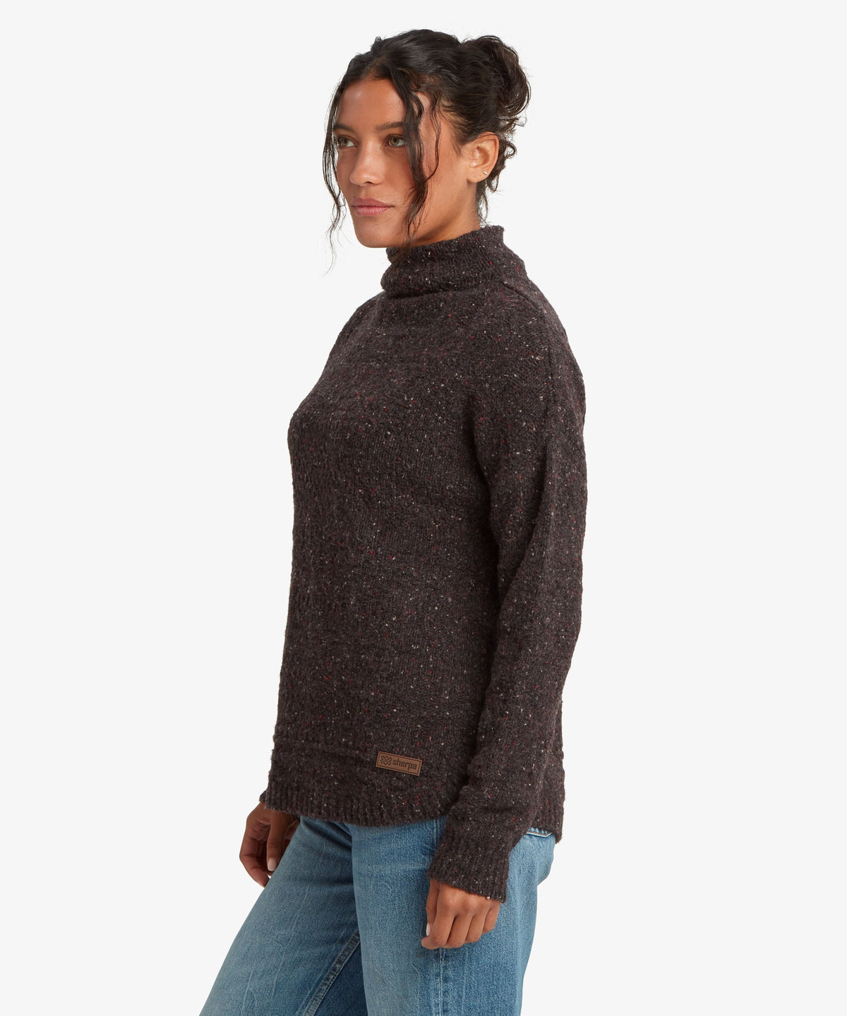 A female model, shown from the side, wearing the black Yuden Sweater by Sherpa Adventure Gear.